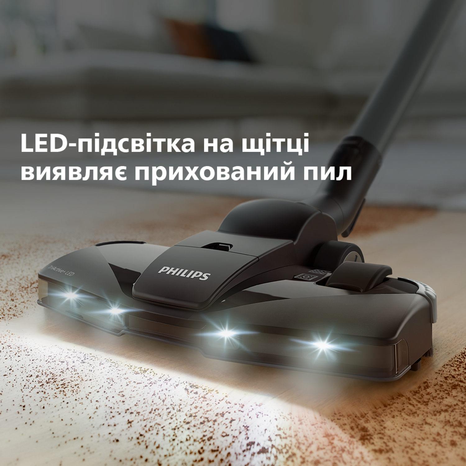 Zbliżenie czarnej głowicy odkurzacza z jasnymi światłami LED na brązowej powierzchni.