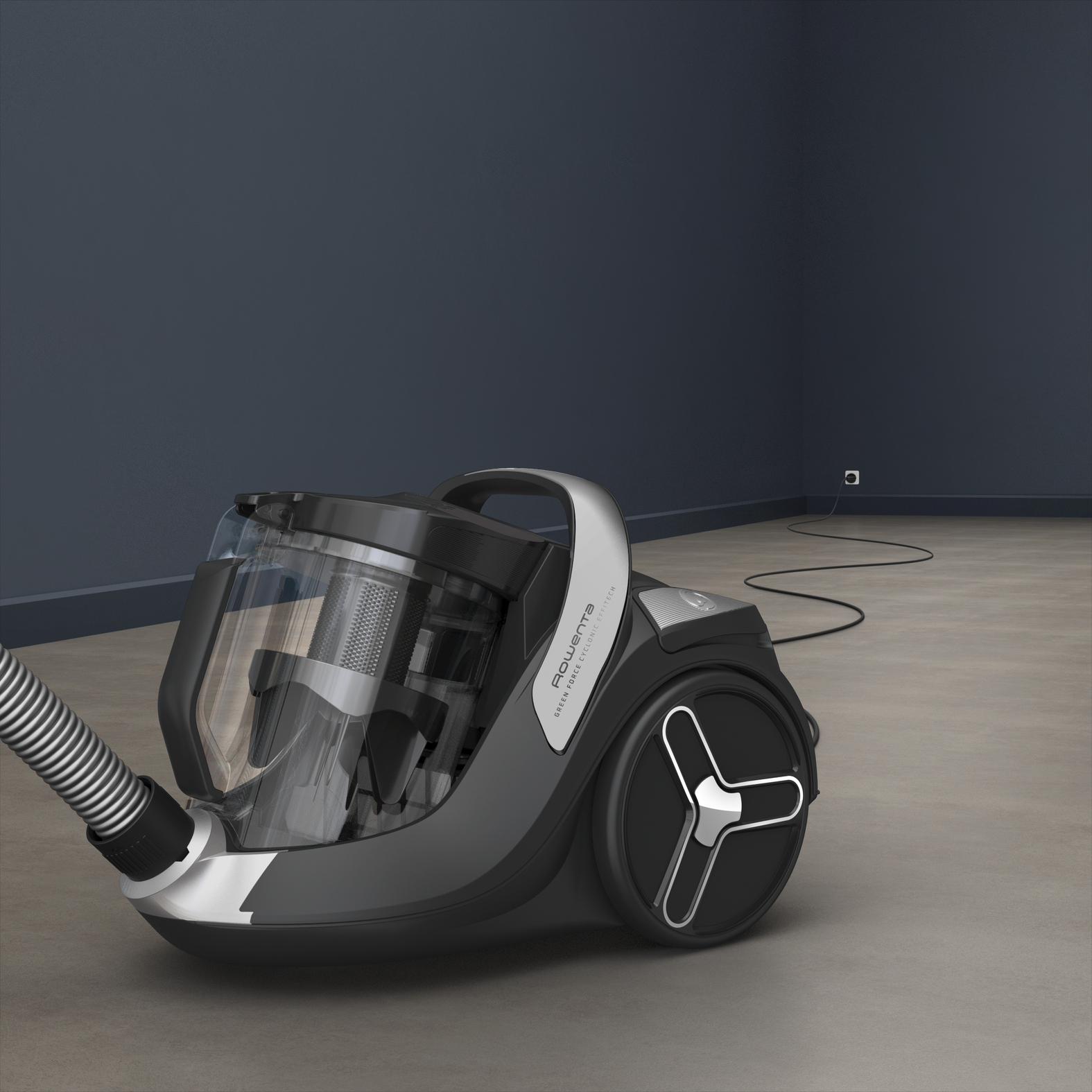 Czarny i szary odkurzacz na jasnobrązowej podłodze, ciemnoniebieskie tło ściany.