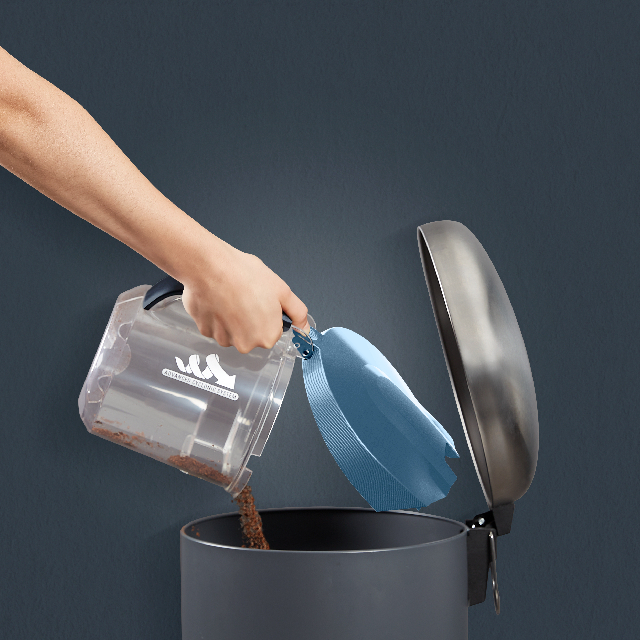 Hand entleert einen Staubsaugerbehälter in einen Mülleimer. Braune Ablagerungen. Blauer Deckel.