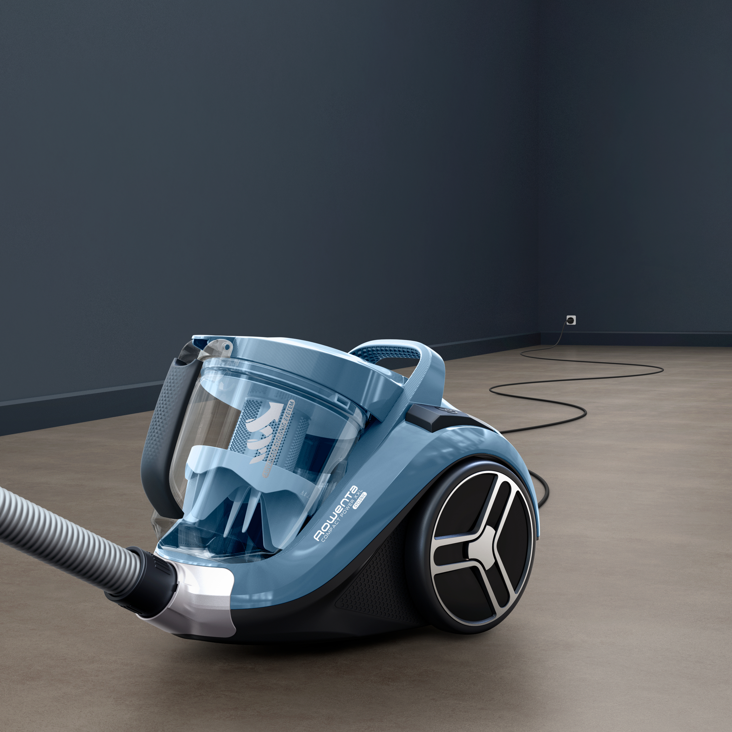 Blauer Staubsauger auf braunem Boden. Der Schlauch ist befestigt, mit schwarzem Netzkabel.