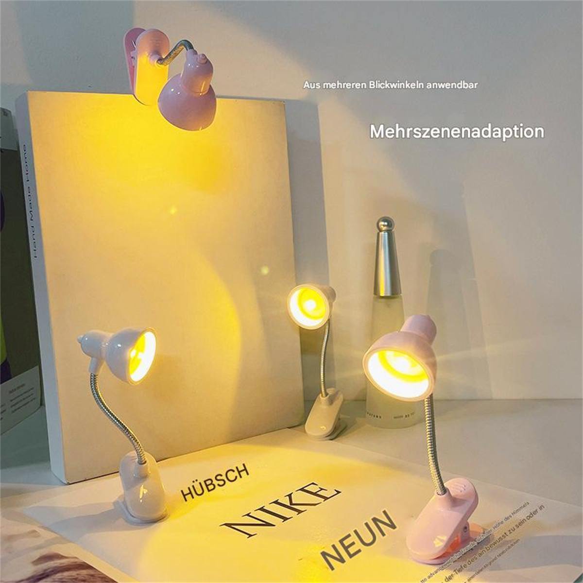Drei kleine rosa Buchlichter auf einem Tisch mit einem Buch. Gelbes Licht. Weißer Hintergrund.