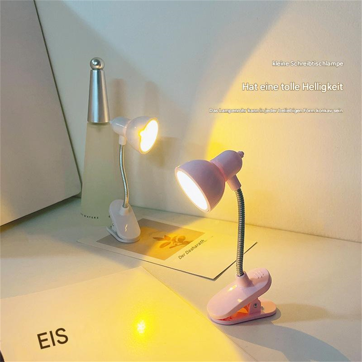 Zwei kleine, rosa Schreibtischlampen mit flexiblen Hälsen, jede mit einer Glühbirne, stehen auf einem Tisch.