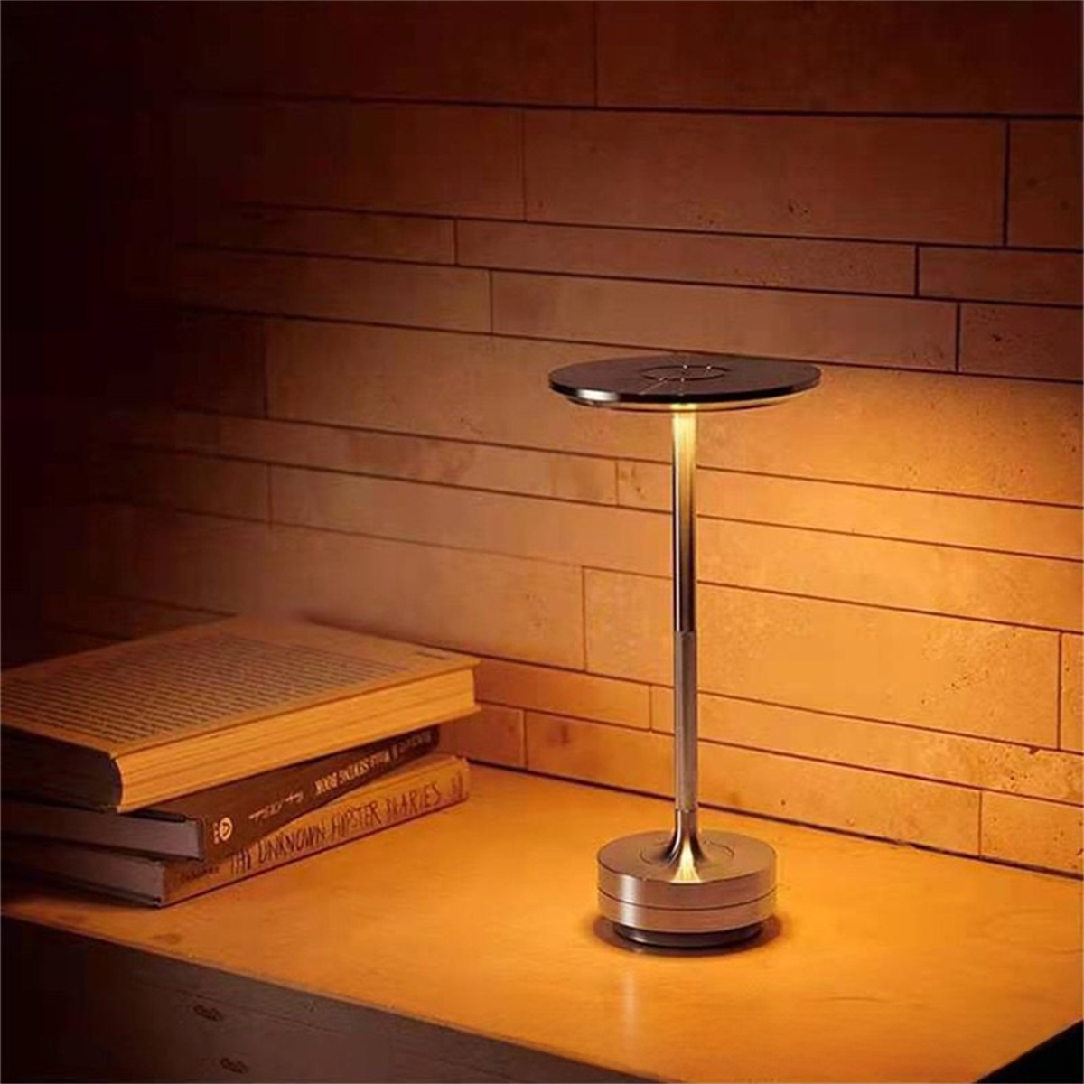 Eine silberne Nachttischlampe auf einem Nachttisch aus Holz, mit Büchern im Vordergrund.