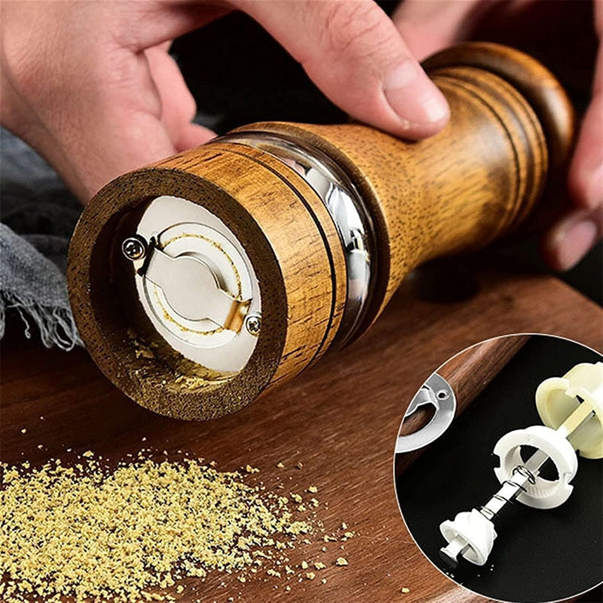 Holzpfeffermühle mit Pfeffer, Hände halten sie. Einsatz zeigt den Mahlmechanismus.