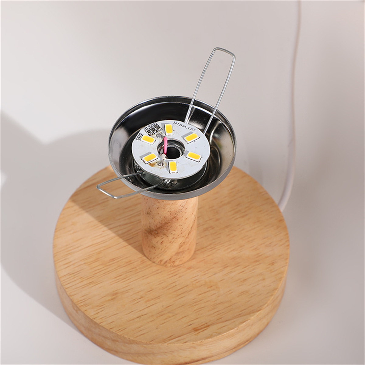 Ein hölzerner Lampensockel mit einer metallischen Lampenkomponente. Die Lampe zeigt die Lichtquelle.
