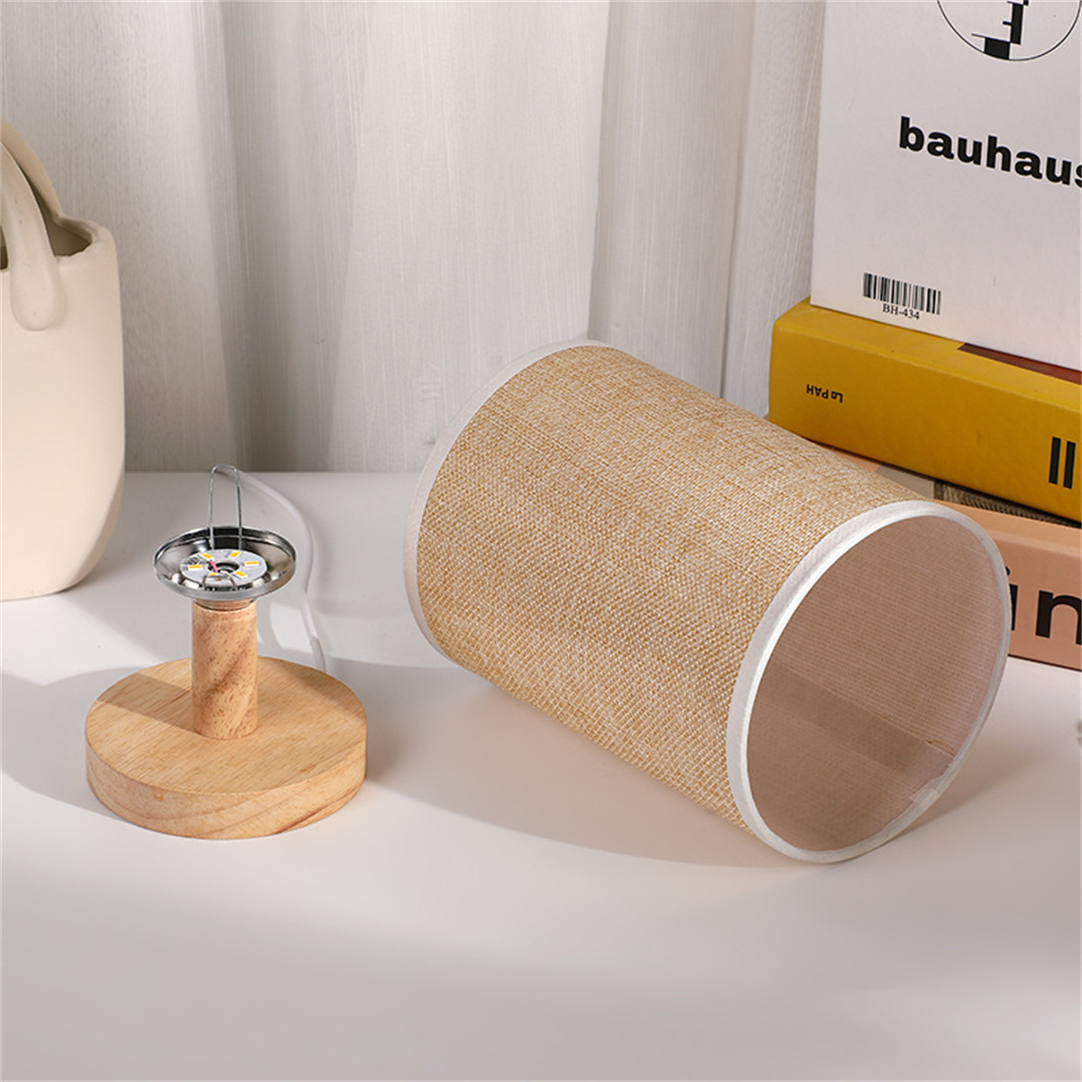 Eine beige Zylinderlampe und ein Holzsockel mit einem kleinen Metallelement.