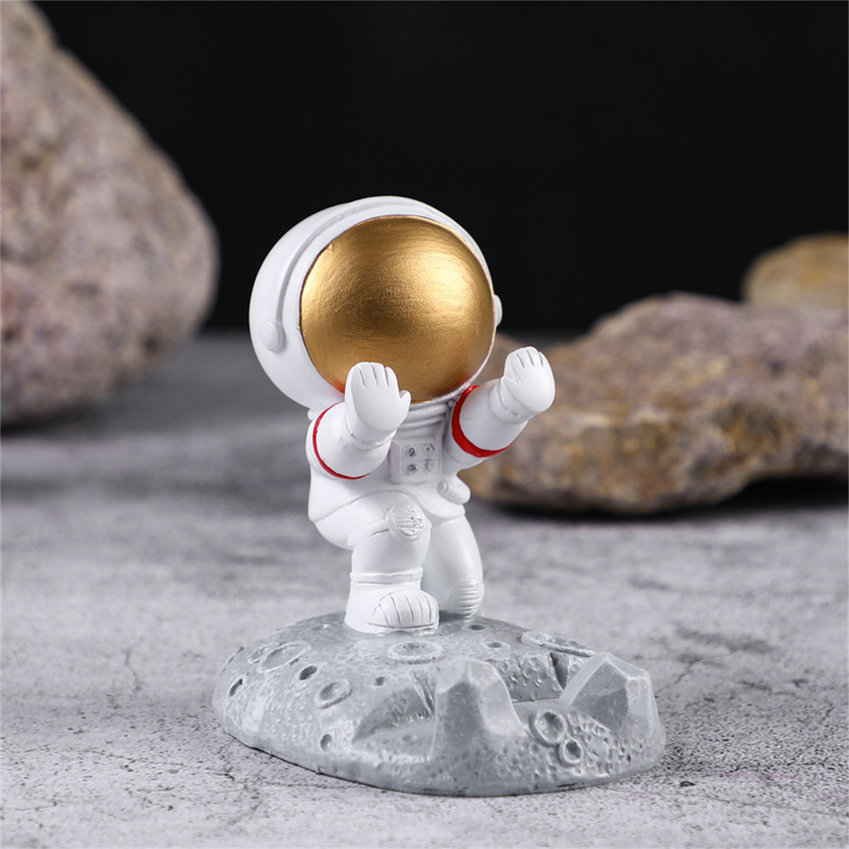 Eine weiße Astronautenfigur auf einer grauen Mondbasis, die Arme in einer Begrüßungsgeste hebt.