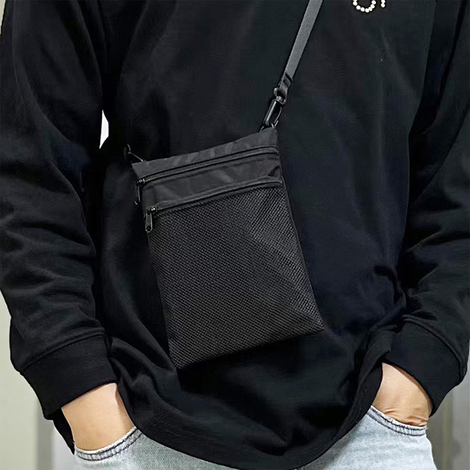 Eine schwarze Umhängetasche mit Netztasche und Riemen.