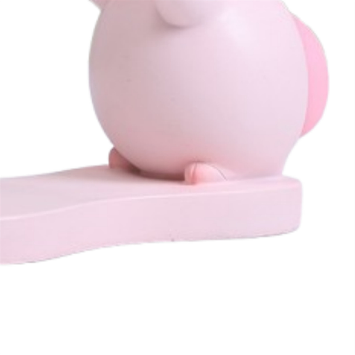 Nahaufnahme eines rosa schweineförmigen Nachtlichts auf einer rosa Plattform, weißer Hintergrund.
