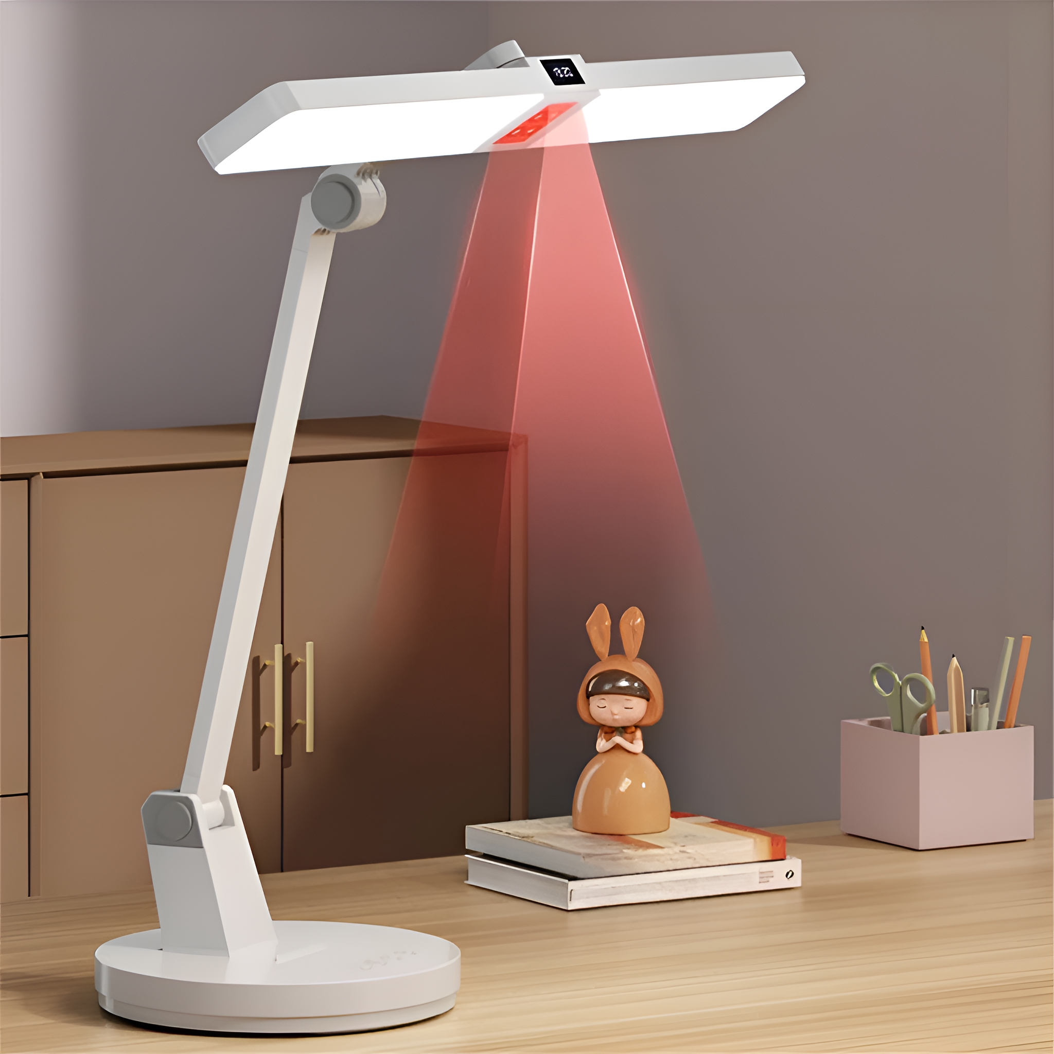 Weiße Schreibtischlampe mit rotem Lichtstrahl. Eine kleine Figur und Bücher stehen auf dem Schreibtisch.