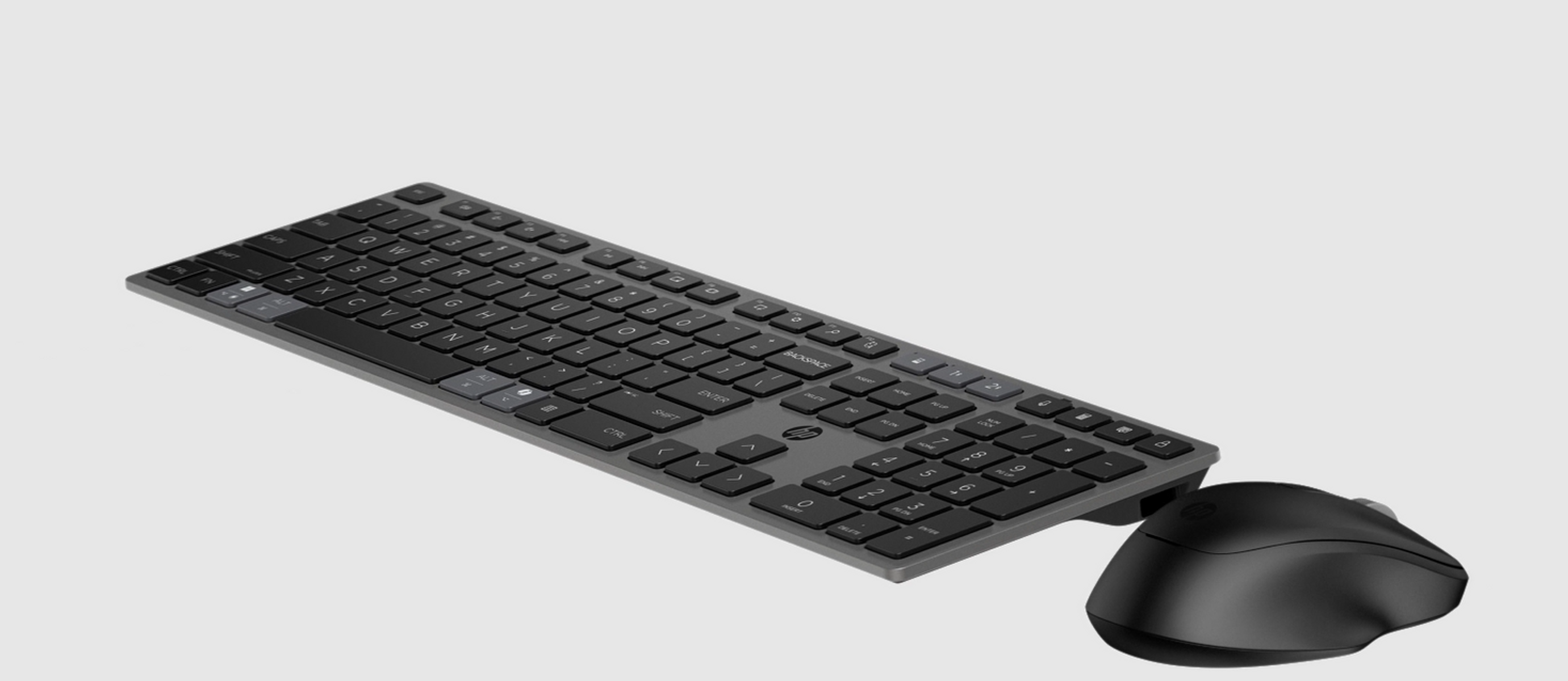 Un set di tastiera e mouse neri su uno sfondo grigio chiaro.