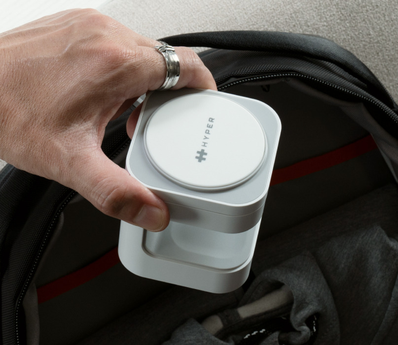 Mano sosteniendo un dispositivo portátil blanco y gris, parcialmente en una bolsa.