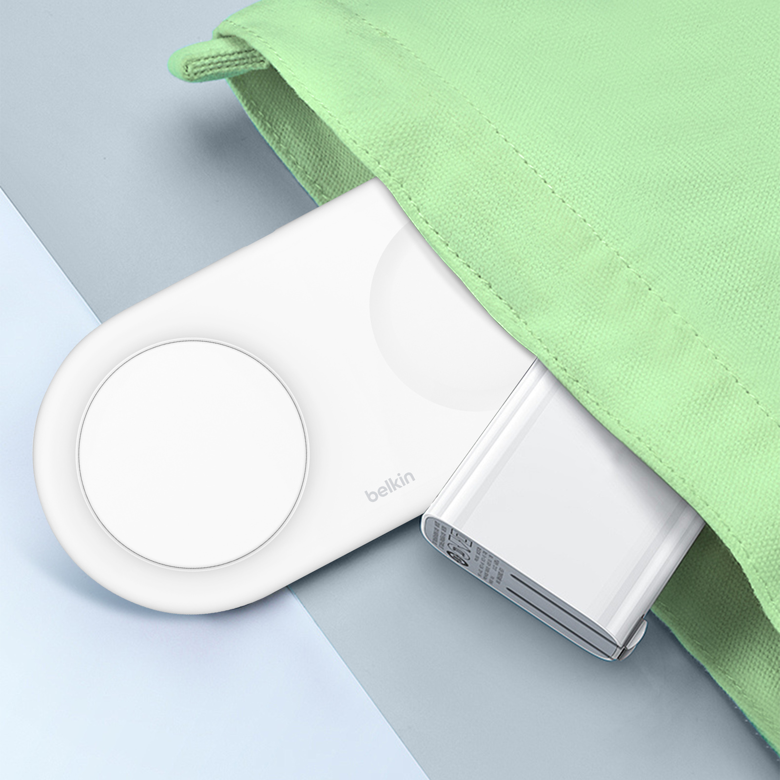 Dispositivo di ricarica Belkin bianco e power bank in una custodia verde. Sfondo azzurro e bianco.