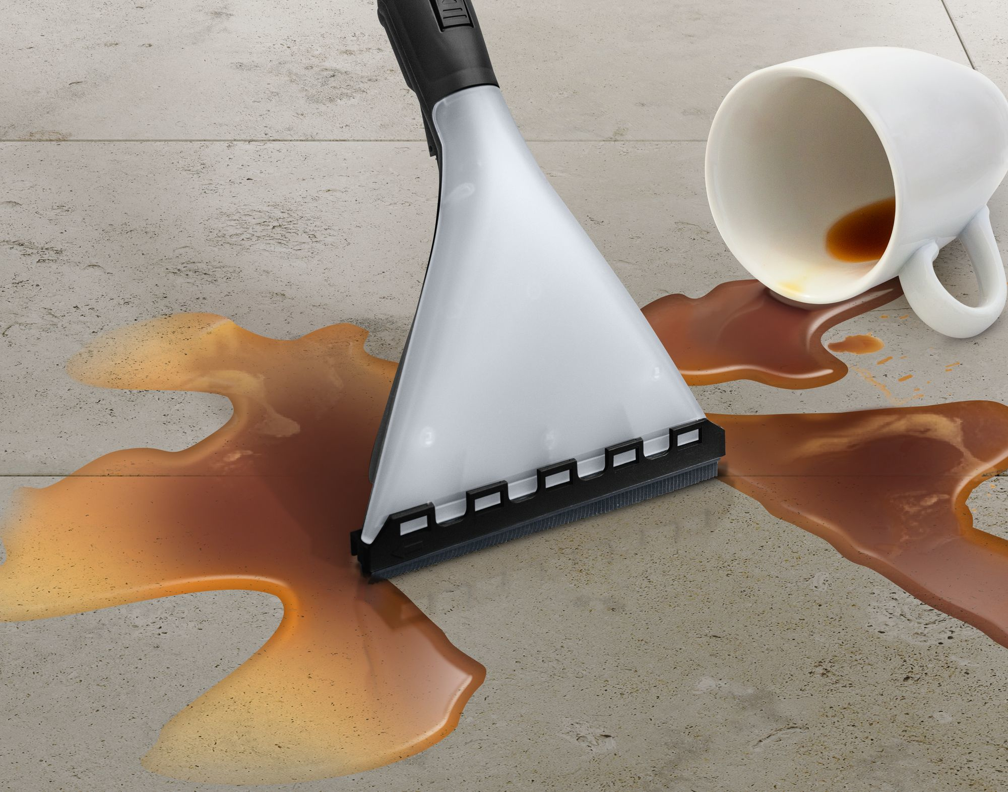 Głowica odkurzacza na podłodze pokrytej rozlaną kawą i przewróconym kubkiem.