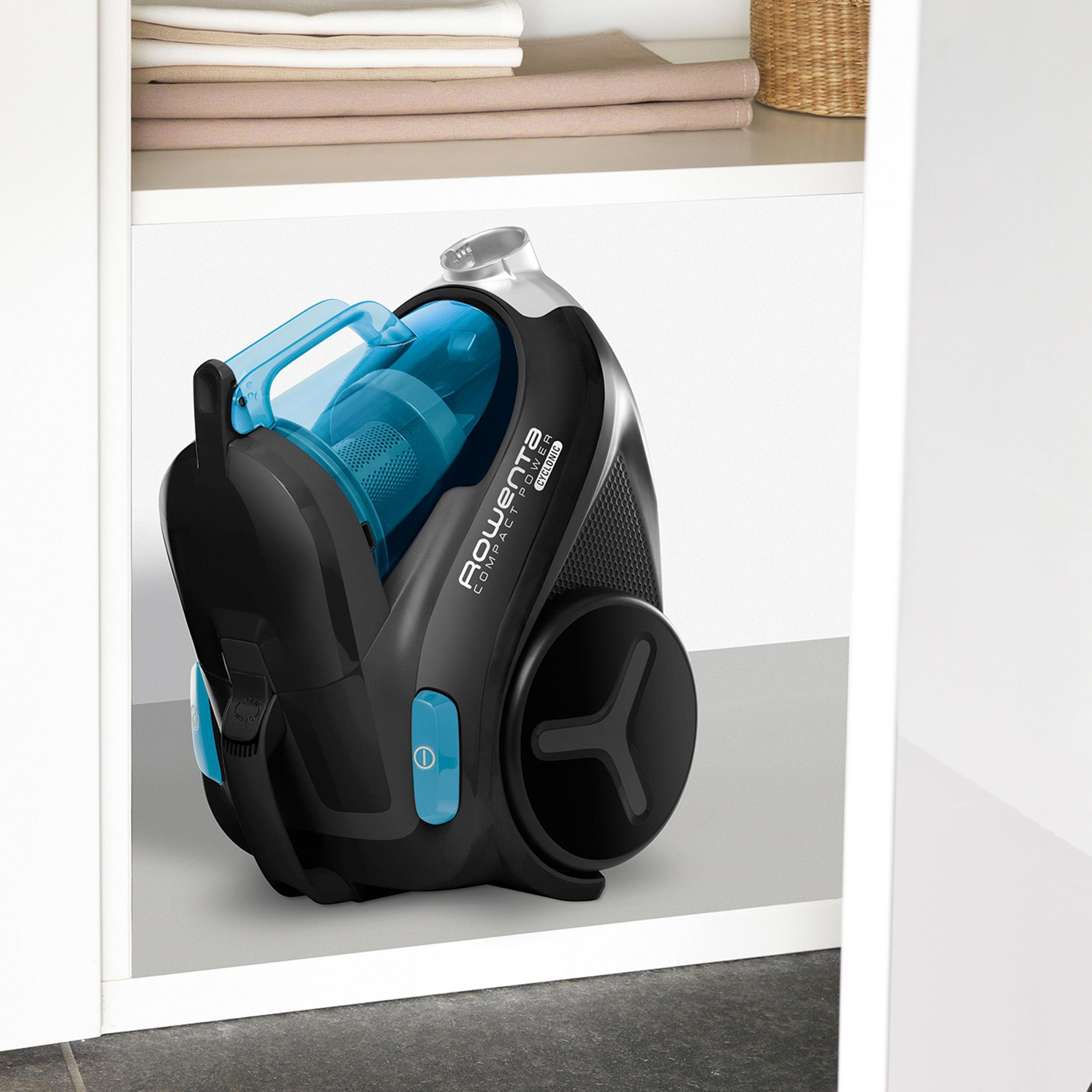 Złożony czarny odkurzacz. Jest przechowywany w białej szafce. Niebieskie detale.