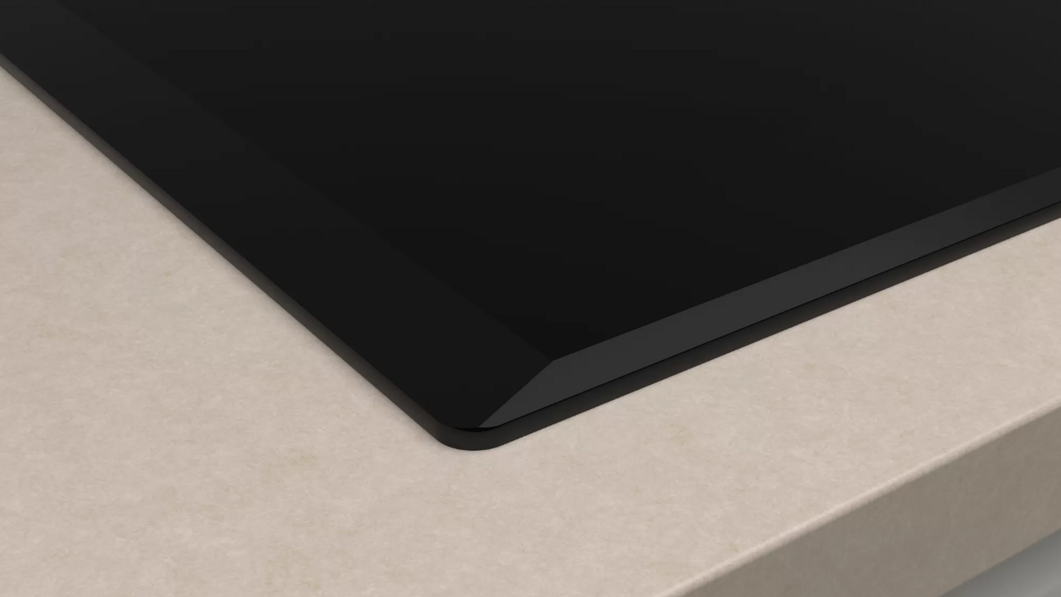 Zbliżenie czarnej płyty kuchennej na beżowym blacie. Powierzchnia jest gładka i odbijająca światło.