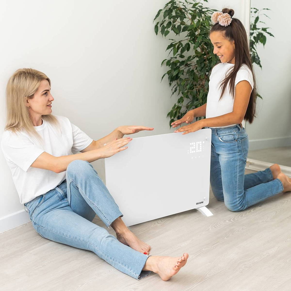 Een vrouw en een meisje staan ​​bij een witte kachel. Beiden dragen jeans en witte shirts.