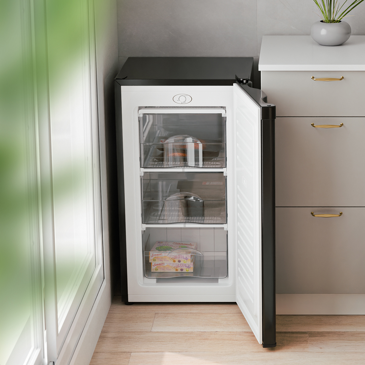 A black freezer with open door, filled with food containers, next to a white cabinet.