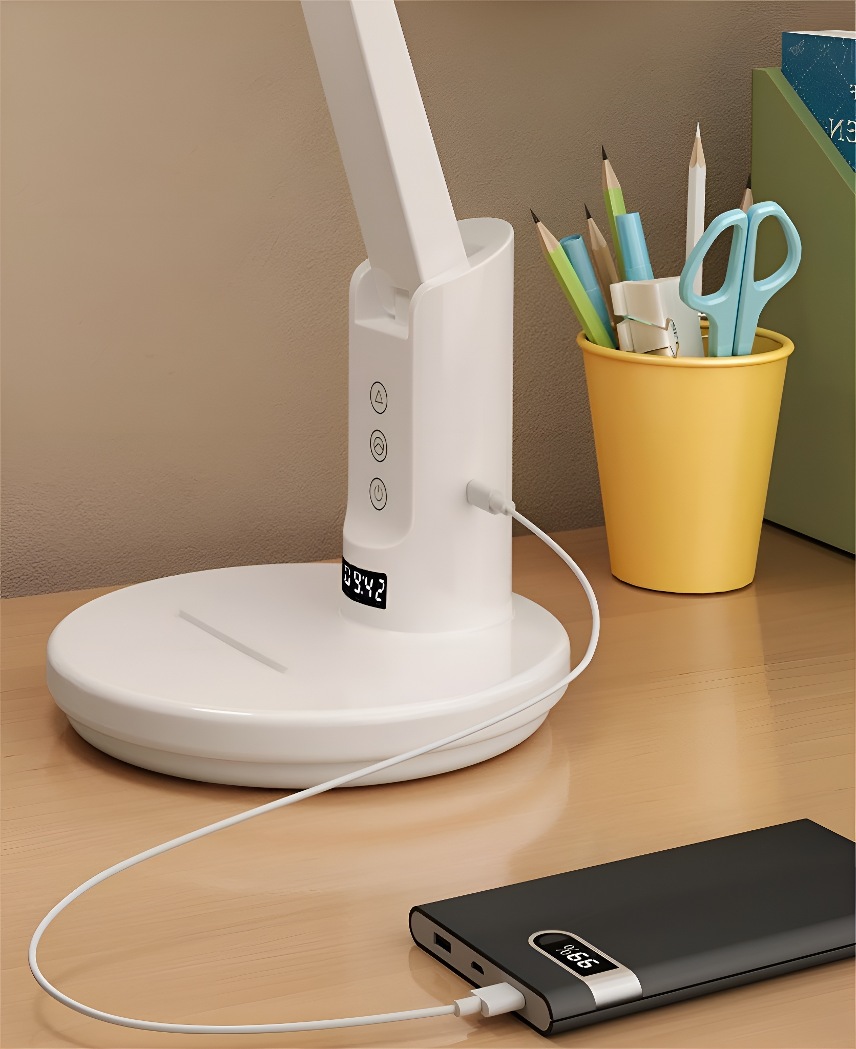 Eine weiße Schreibtischlampe mit Digitalanzeige, die 09:42 anzeigt, eine Powerbank wird geladen, Stifte und Schere.