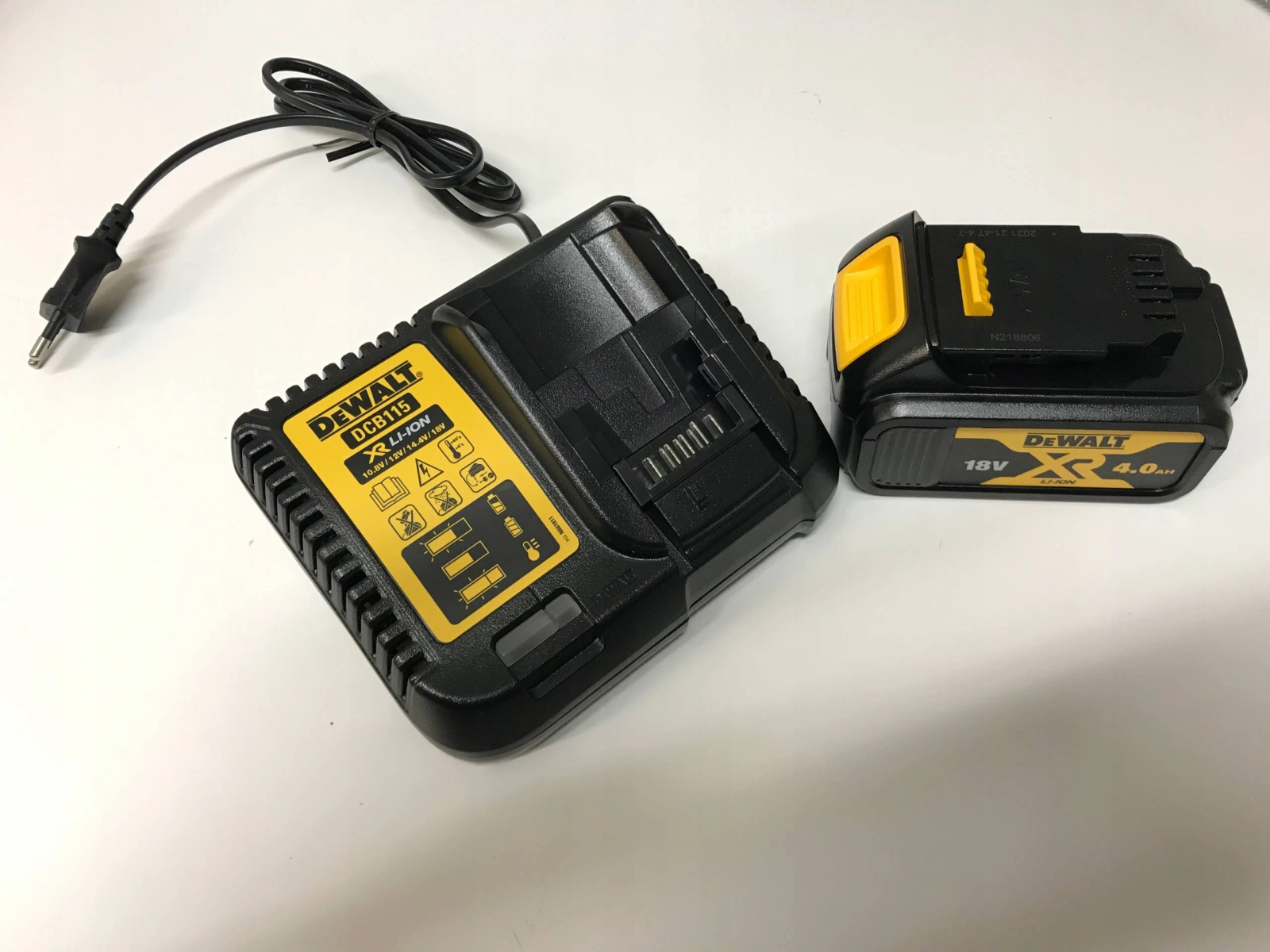 Caricabatterie e batteria per utensili elettrici neri e gialli su sfondo bianco.
