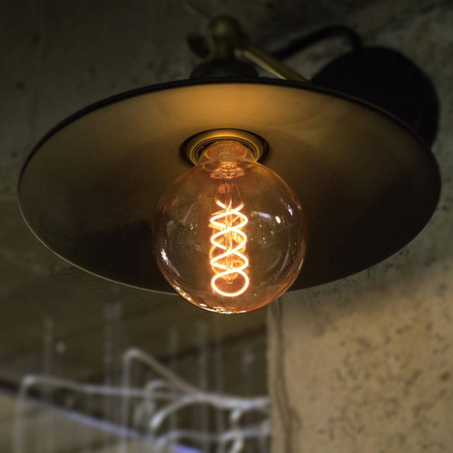 Lampada in stile vintage con lampadina rotonda e filamento a spirale, appesa al soffitto.