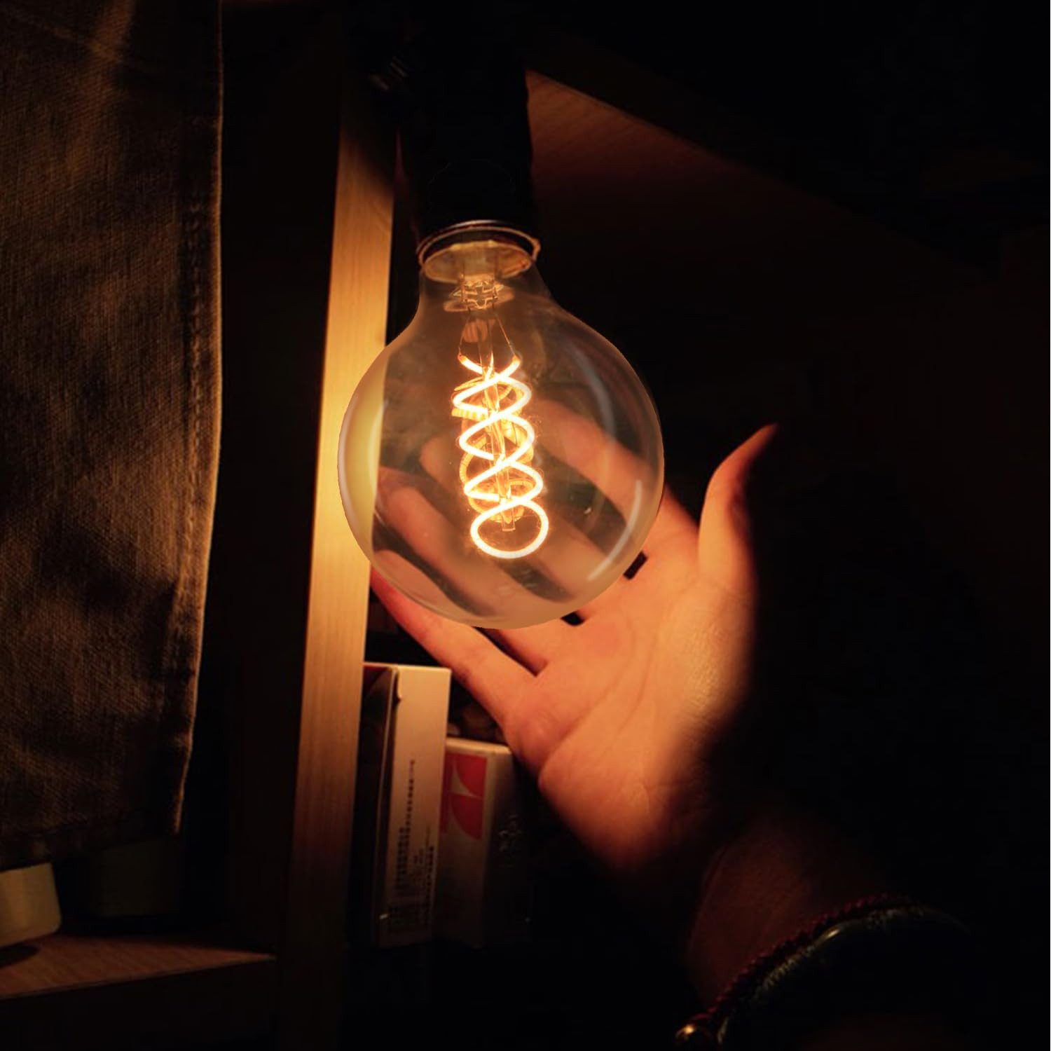 Una mano che raggiunge una lampadina a filamento a spirale illuminata.