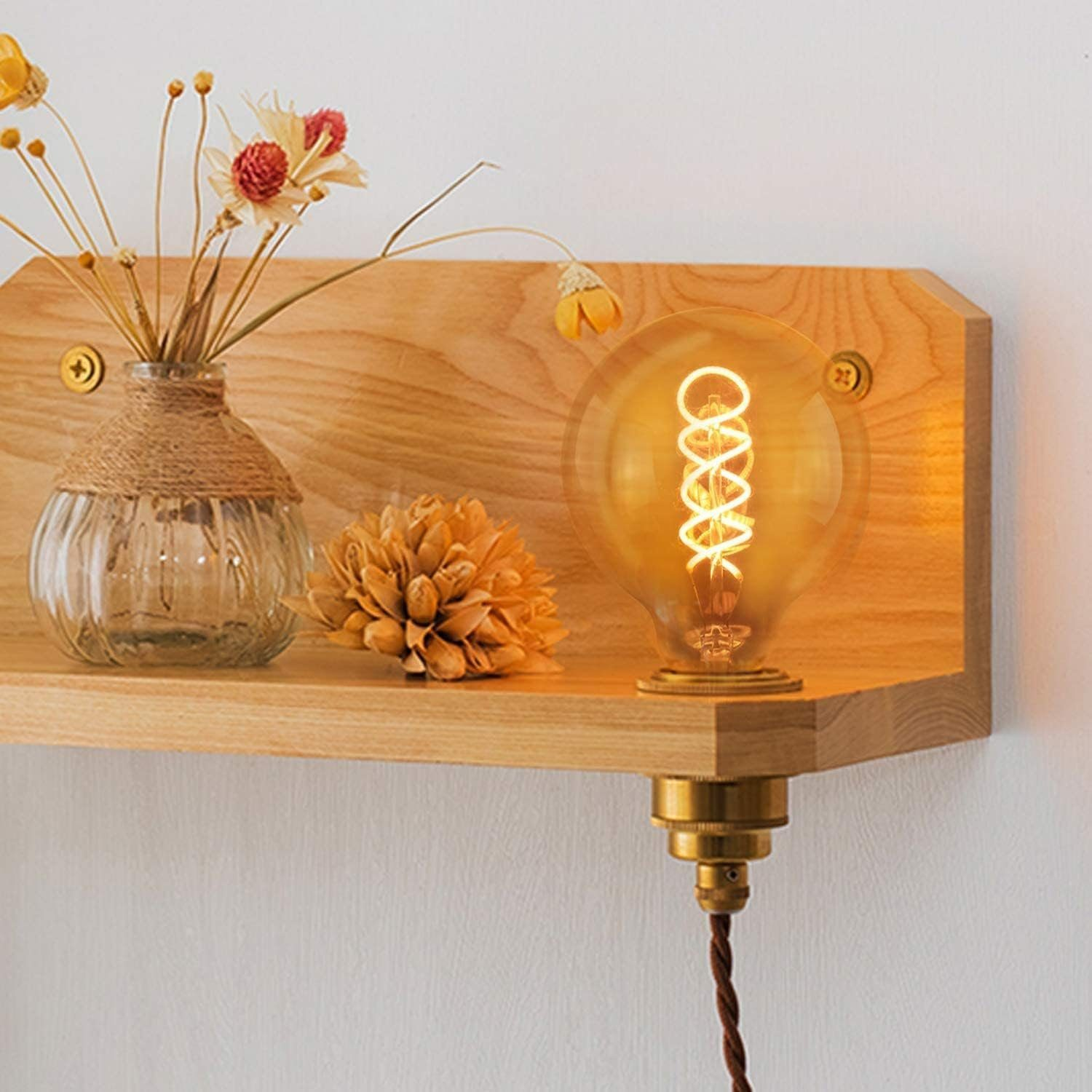 Glühbirne in einem Holzregal mit Blumen und einer Vase.
