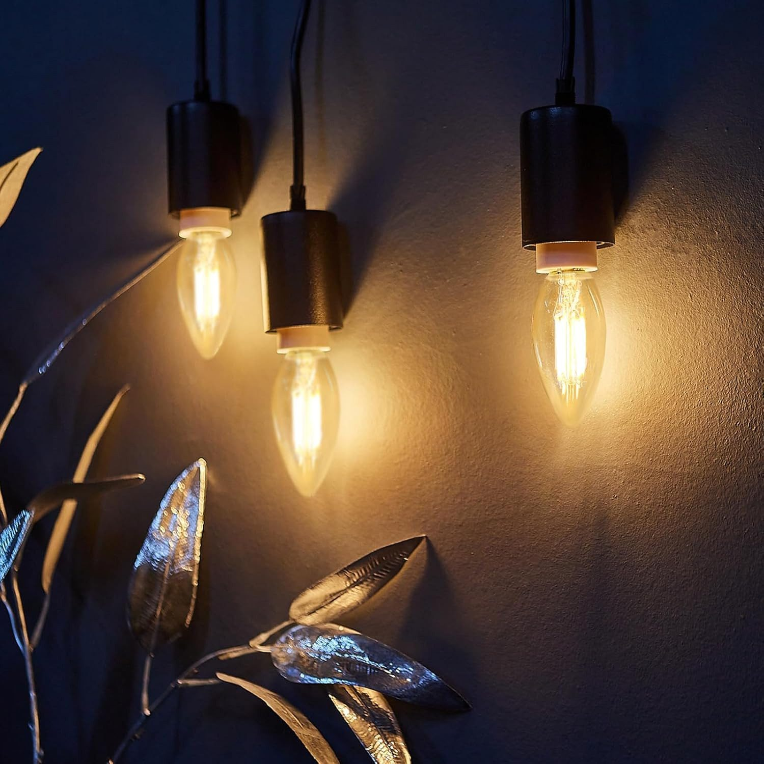 Tre lampadine appese con luce calda.