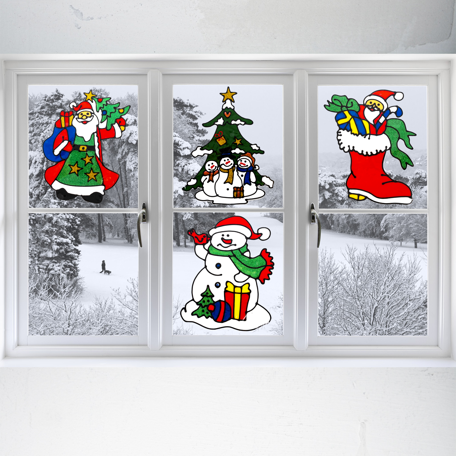 Weihnachts-Fensterdekorationen auf einem weißen Rahmen. Schneebedeckte Bäume und eine Person sind draußen sichtbar.