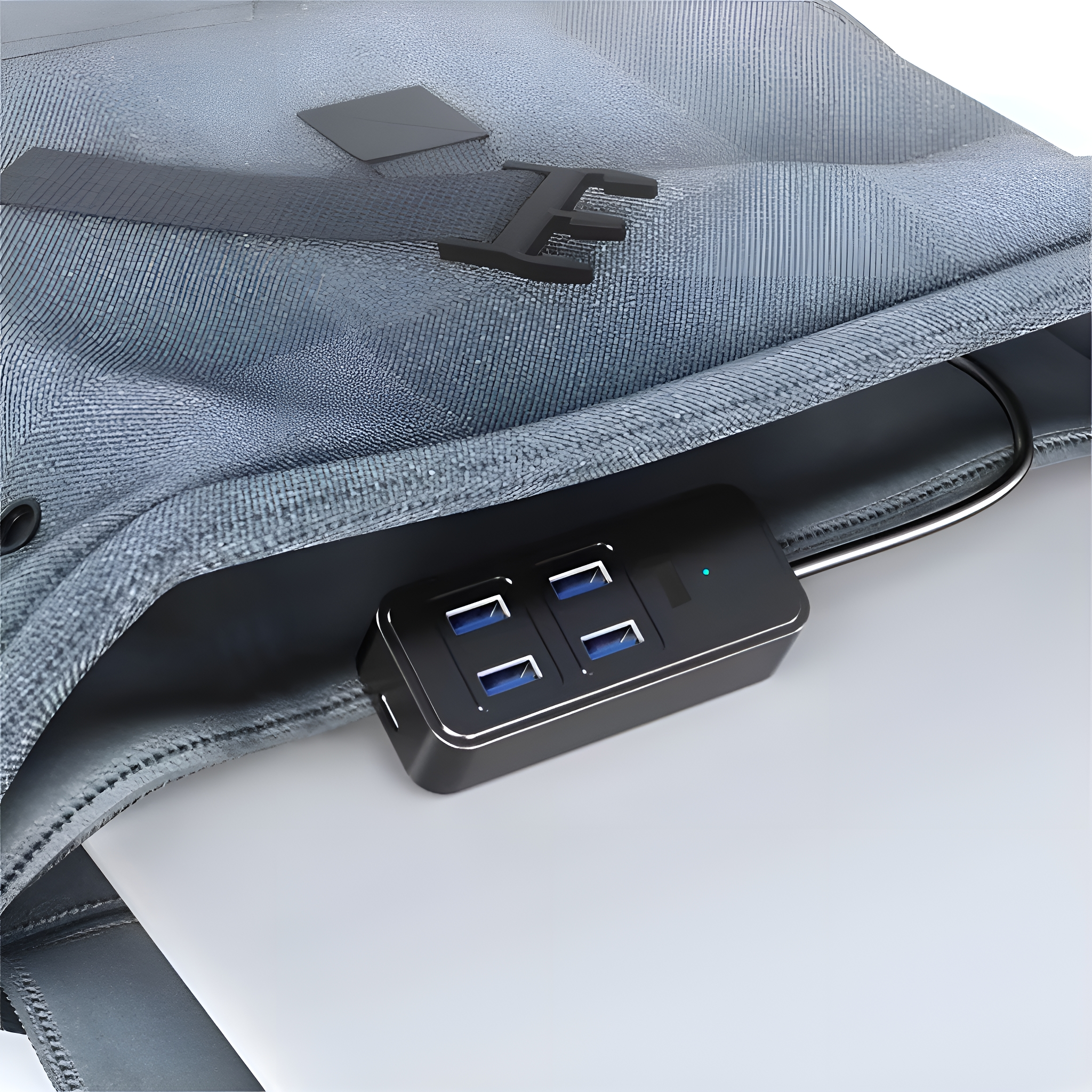 Schwarzer USB-Hub, der an einen Laptop angeschlossen ist. Der Hub befindet sich in einer blauen Rucksacktasche.