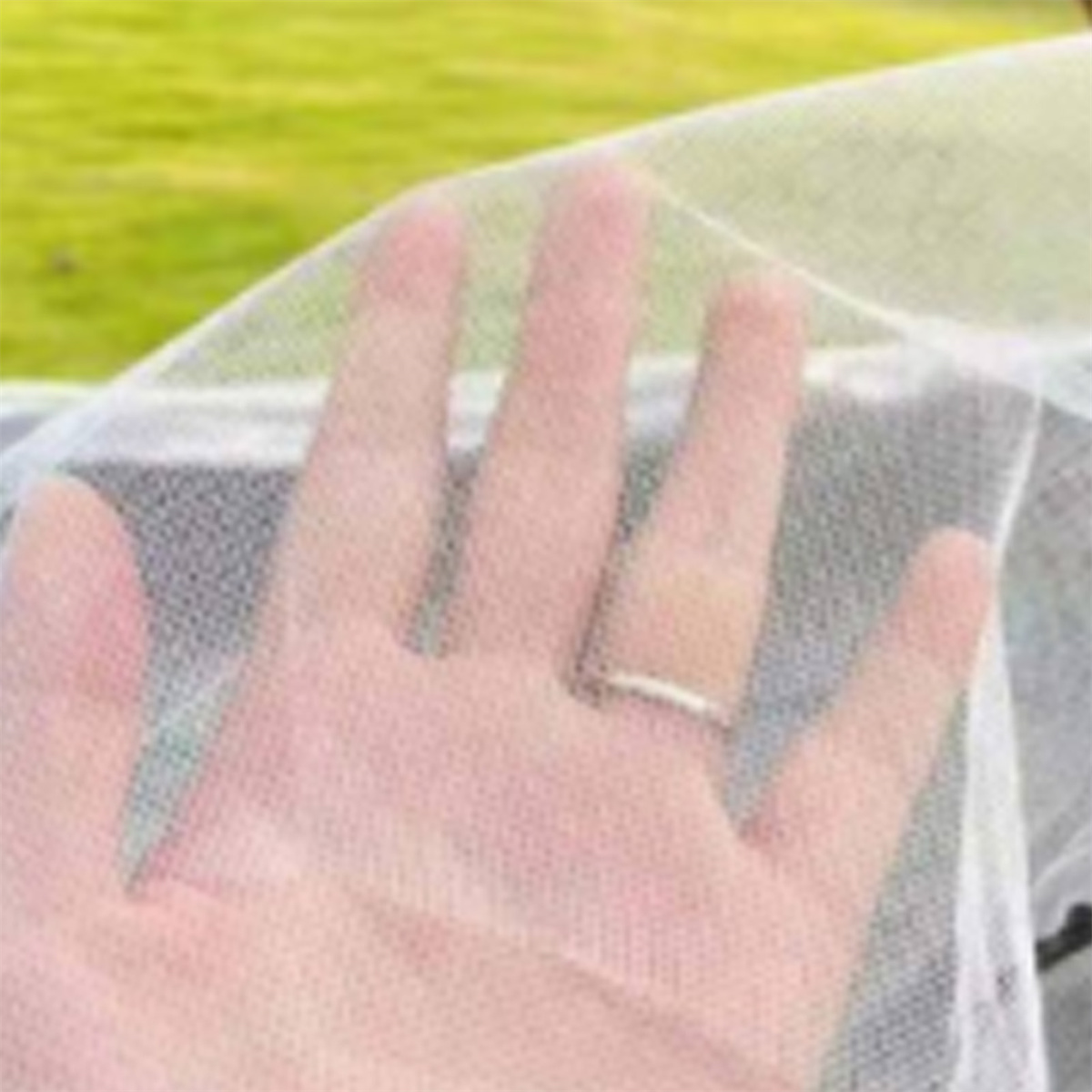 Hand, die durch ein weißes Netzmaterial greift. Grüner Hintergrund.
