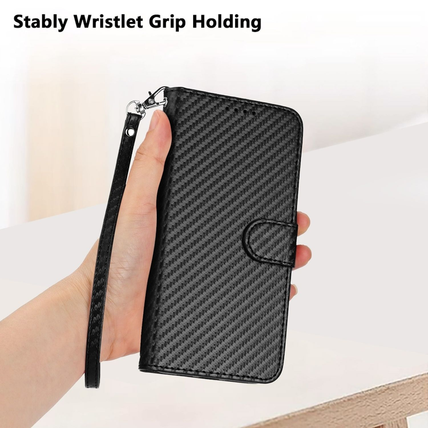 Una mano sosteniendo una funda de teléfono negra con una correa de muñeca. Patrón de fibra de carbono.