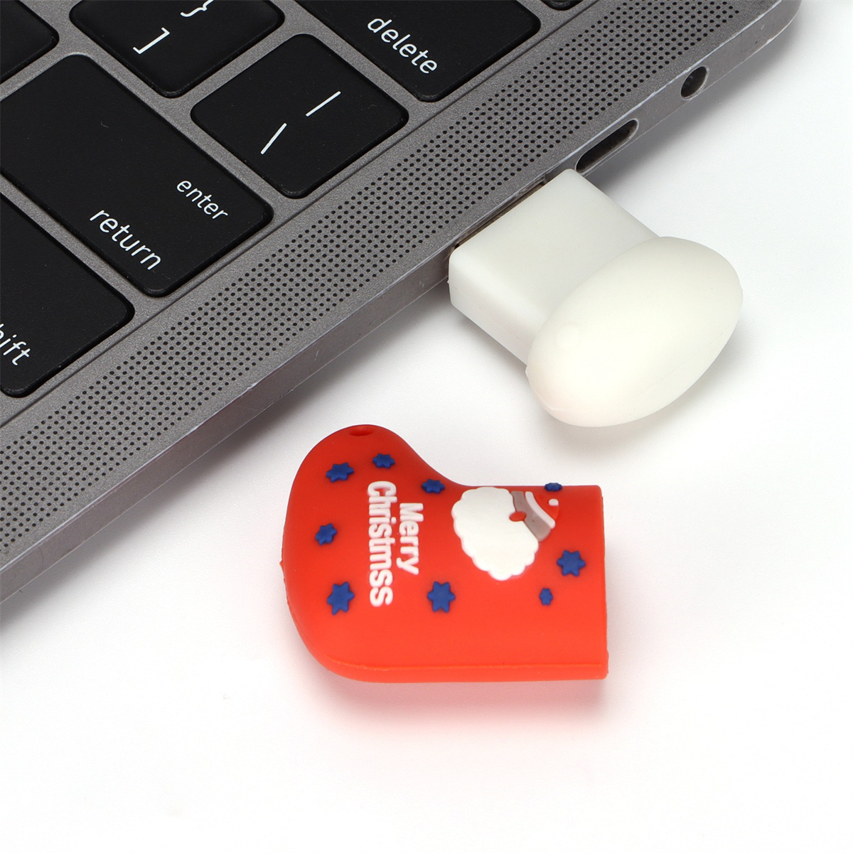 USB-Stick in Form eines Weihnachtsstrumpfes, rot mit Weihnachtsmann und blauen Sternen, in einen Laptop gesteckt.