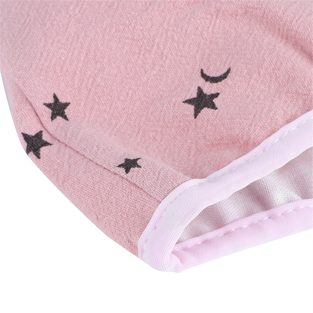 Nahaufnahme von rosa Stoff mit schwarzen Stern- und Mondformen, weißem Besatz, Weichzeichnung.