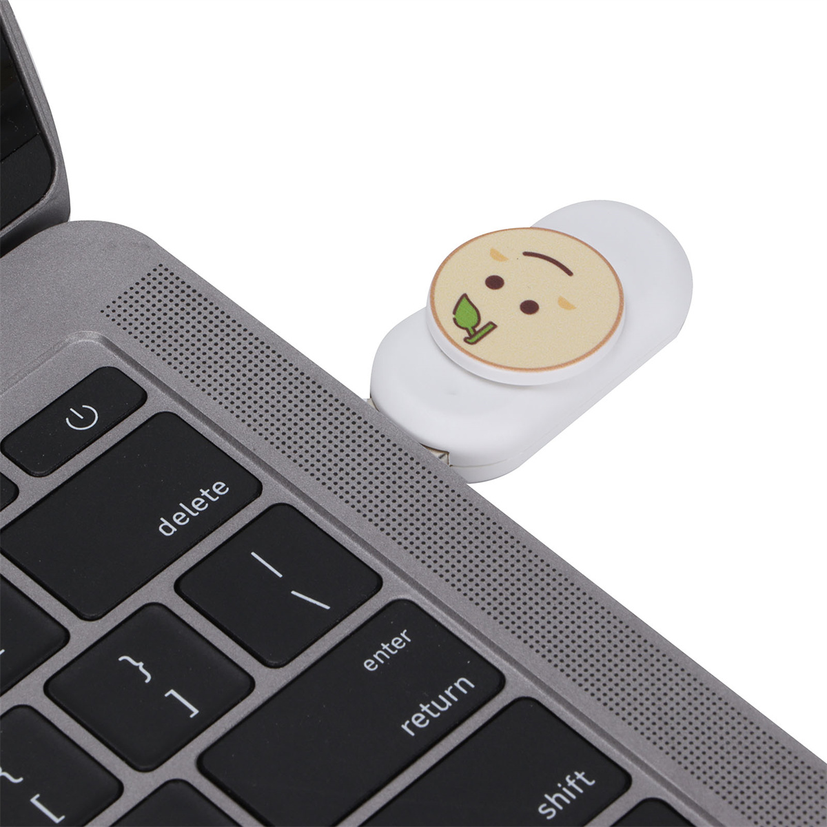 Ein Laptop mit einem weißen USB-Stick, der ein Cartoon-Gesicht zeigt. Der Laptop steht auf einer weißen Oberfläche.