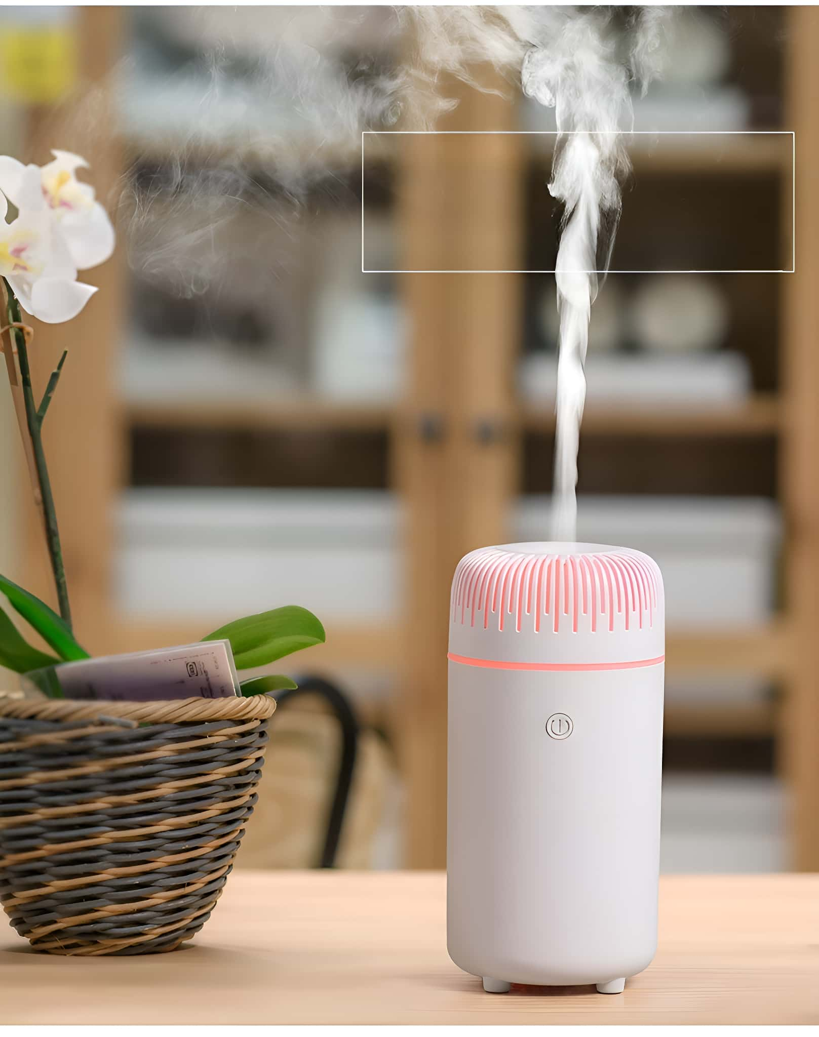 Weißer und rosa Luftbefeuchter. Weißer Dampf steigt von oben auf. Eine Blume und ein Korb stehen auf einem Holztisch.