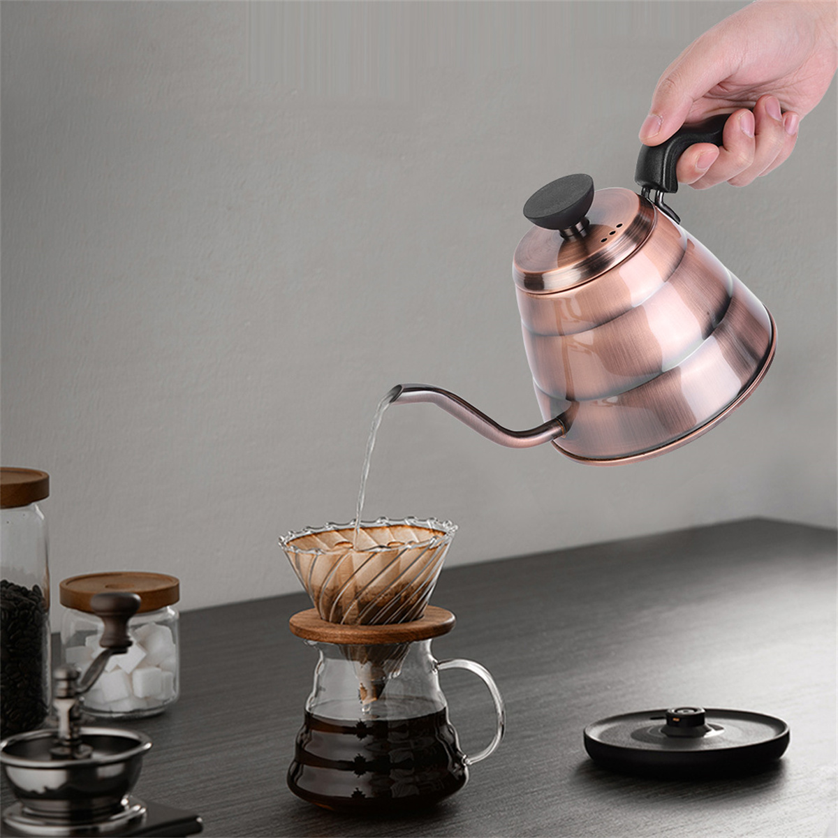 Eine Person gießt heißes Wasser aus einer Kupferkanne in einen Kaffeefilter mit Kaffee.
