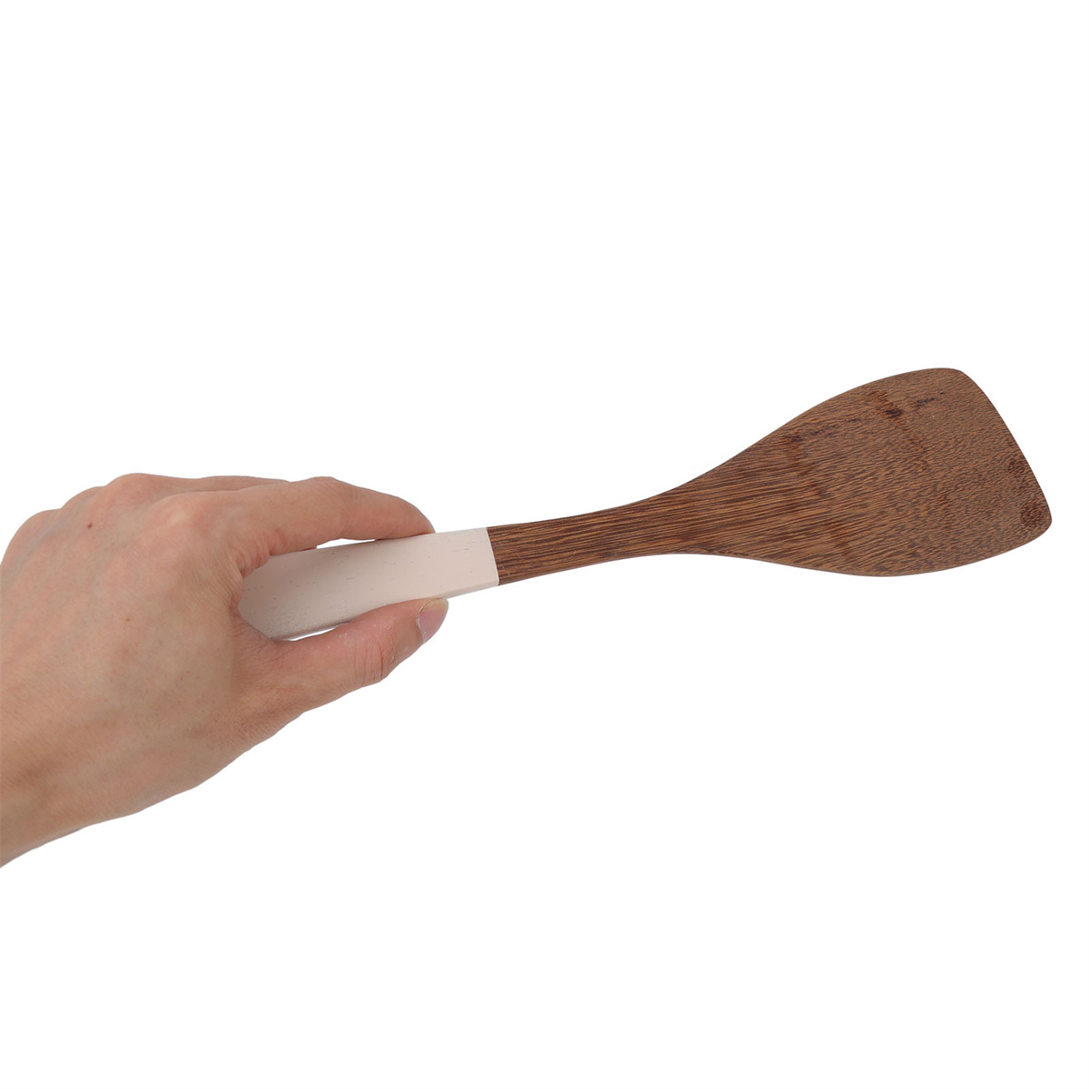 Eine Hand, die einen hölzernen Spatel hält. Der Spatel ist am Ende braun und am Griff weiß.