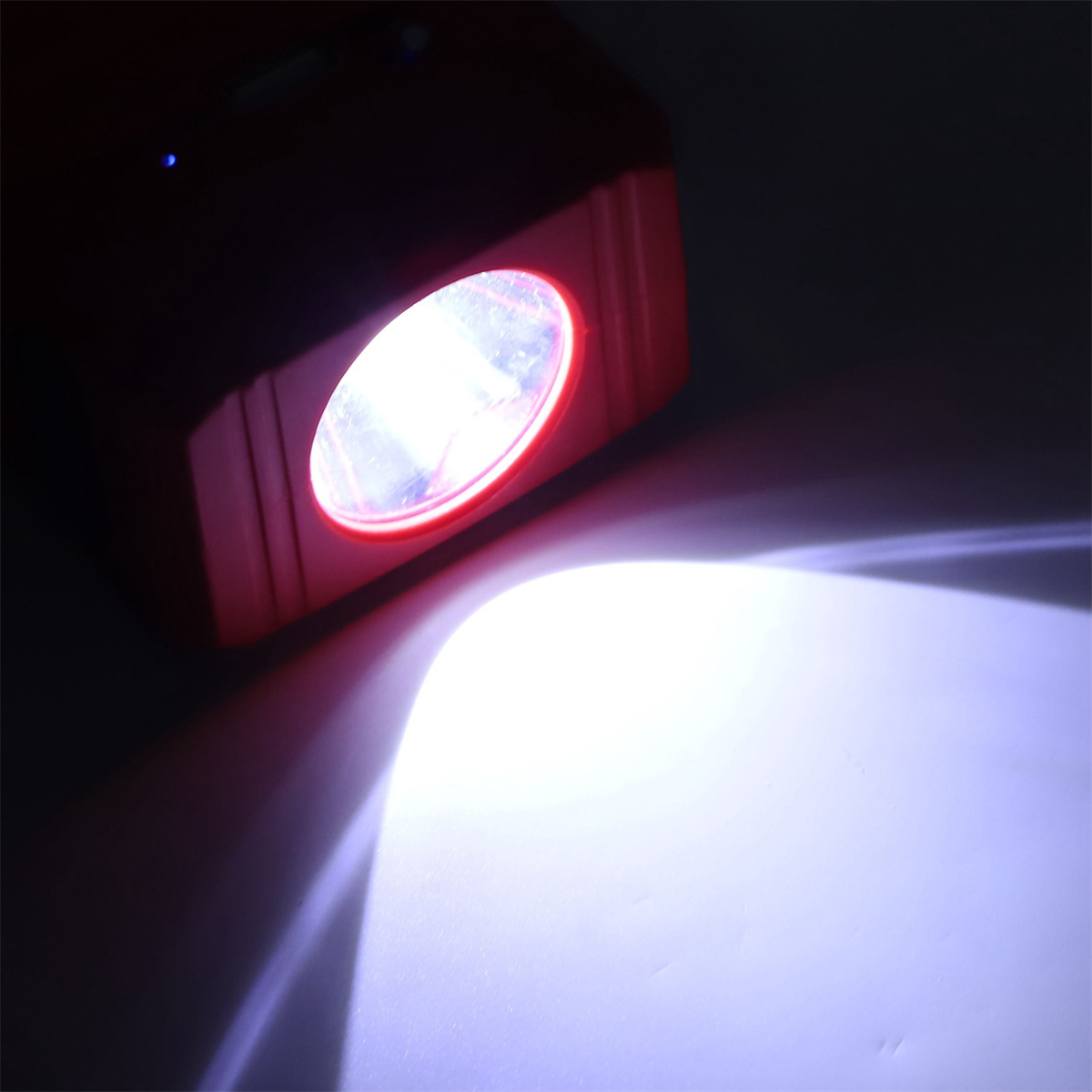 Rote Taschenlampe, die ein helles Licht auf eine weiße Oberfläche wirft.