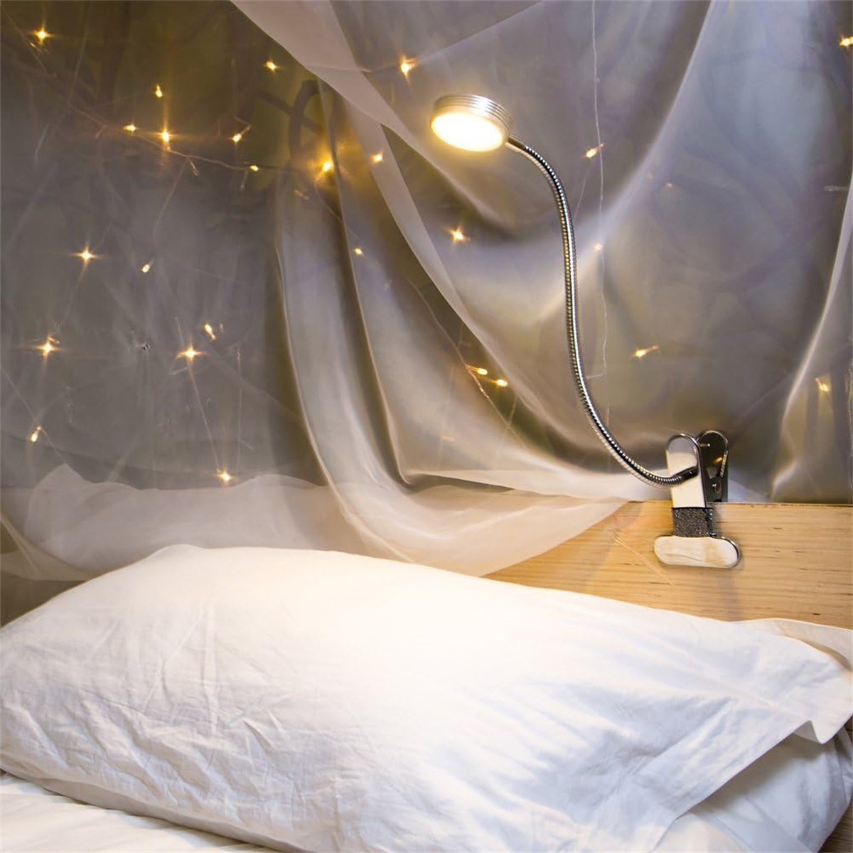 Eine flexible LED-Leselampe, die an einem Bett befestigt ist und ein weißes Kissen und einen transparenten Vorhang beleuchtet.