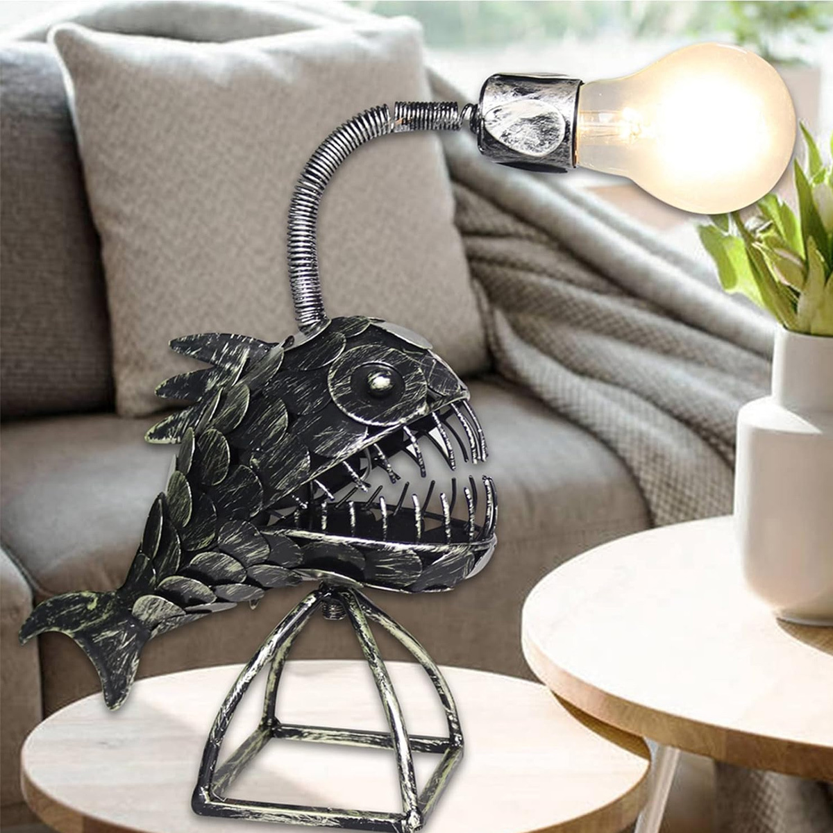 Anglerfisch-Lampe auf einem Tisch. Sie hat ein Fischdesign und eine Glühbirne. Im Hintergrund ist ein Sofa.