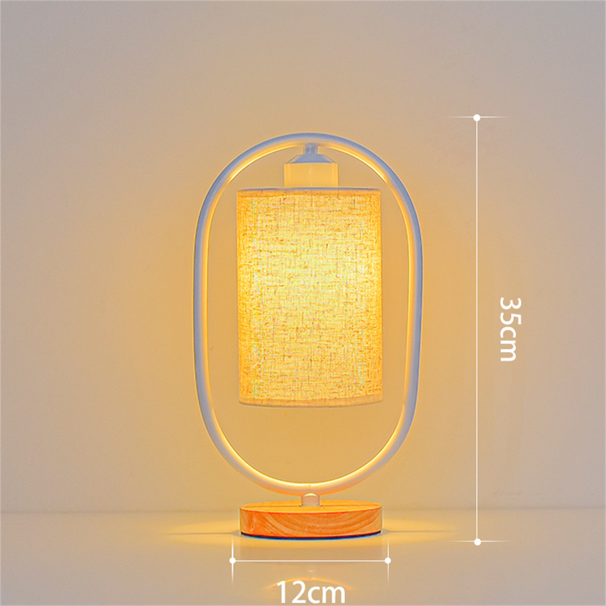 Eine weiße und hölzerne Tischlampe mit ovalem Rahmen und zylindrischem Schirm auf hellem Hintergrund.