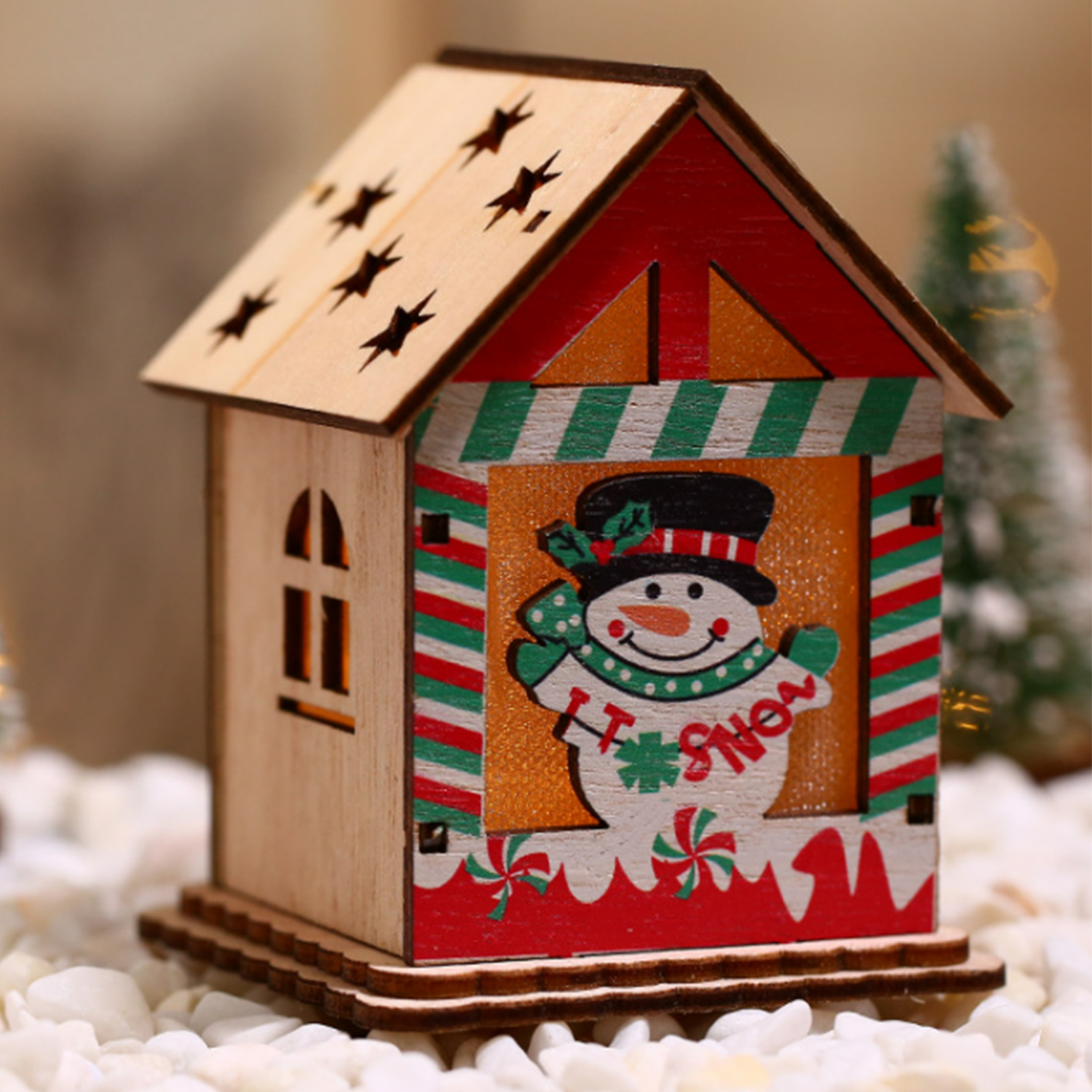 Una casa di Natale decorativa in legno con un pupazzo di neve, stelle e bastoncini di zucchero, illuminata.