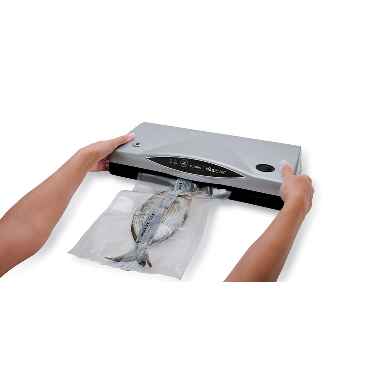 Ręce zamykające rybę w plastikowej torbie za pomocą srebrnej zgrzewarki próżniowej Magic Vac. Białe tło.