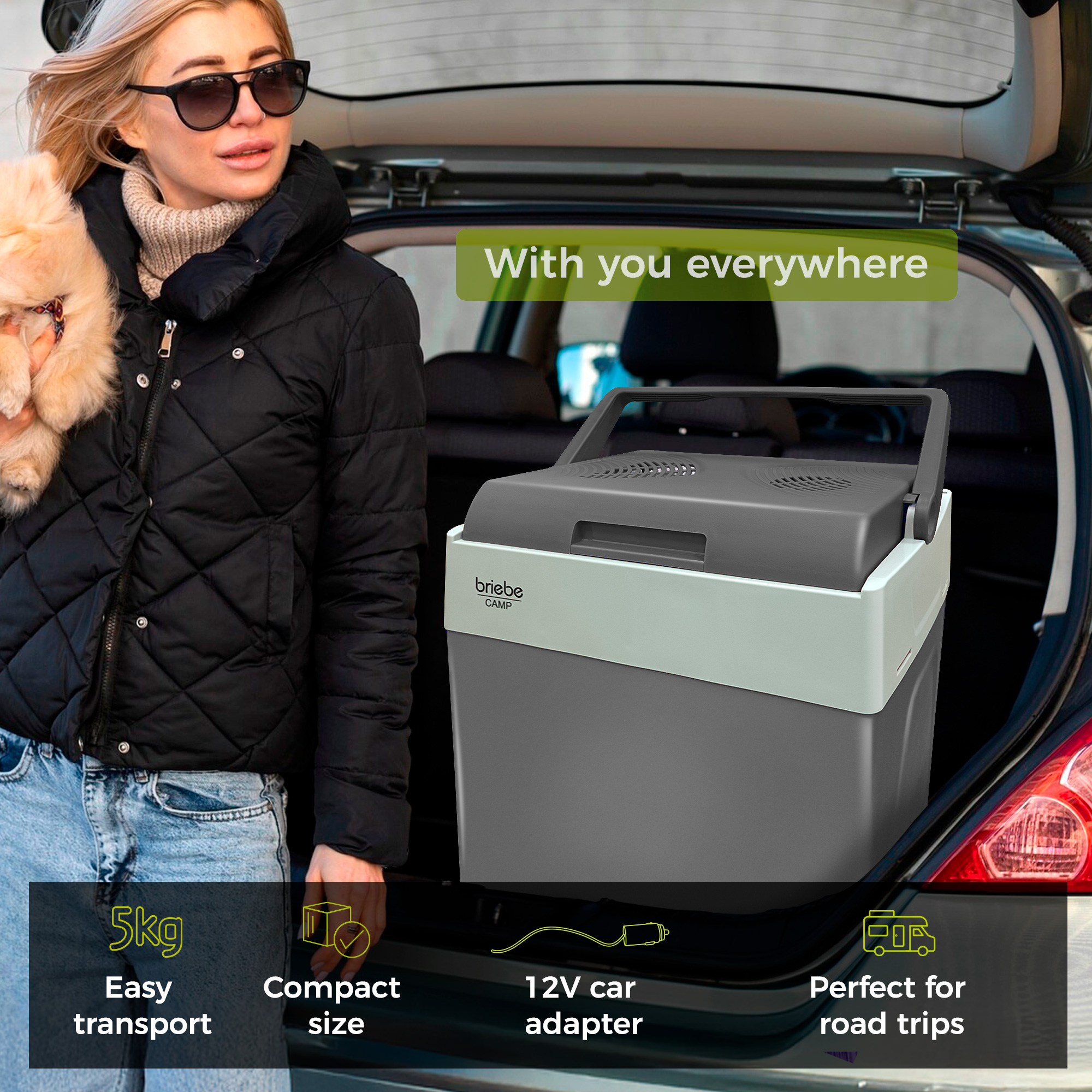 Eine Frau mit Hund neben einem Auto, eine Kühlbox ist im Kofferraum.