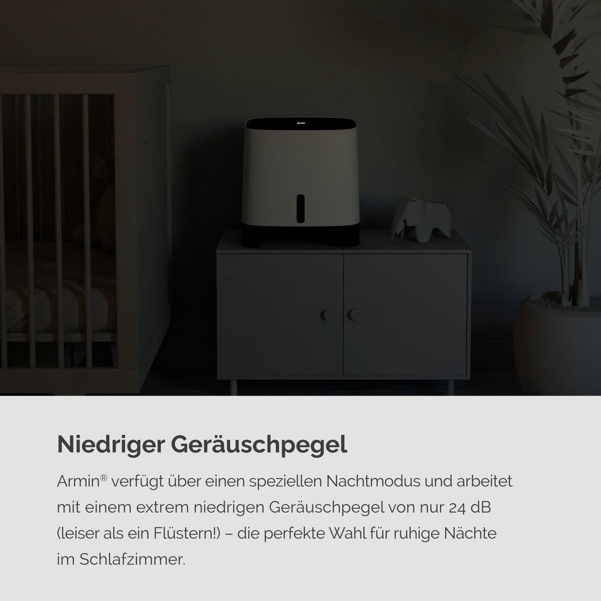 Biały oczyszczacz powietrza z czarnym blatem. Tekst w języku niemieckim. Tło: pokój z łóżeczkiem.