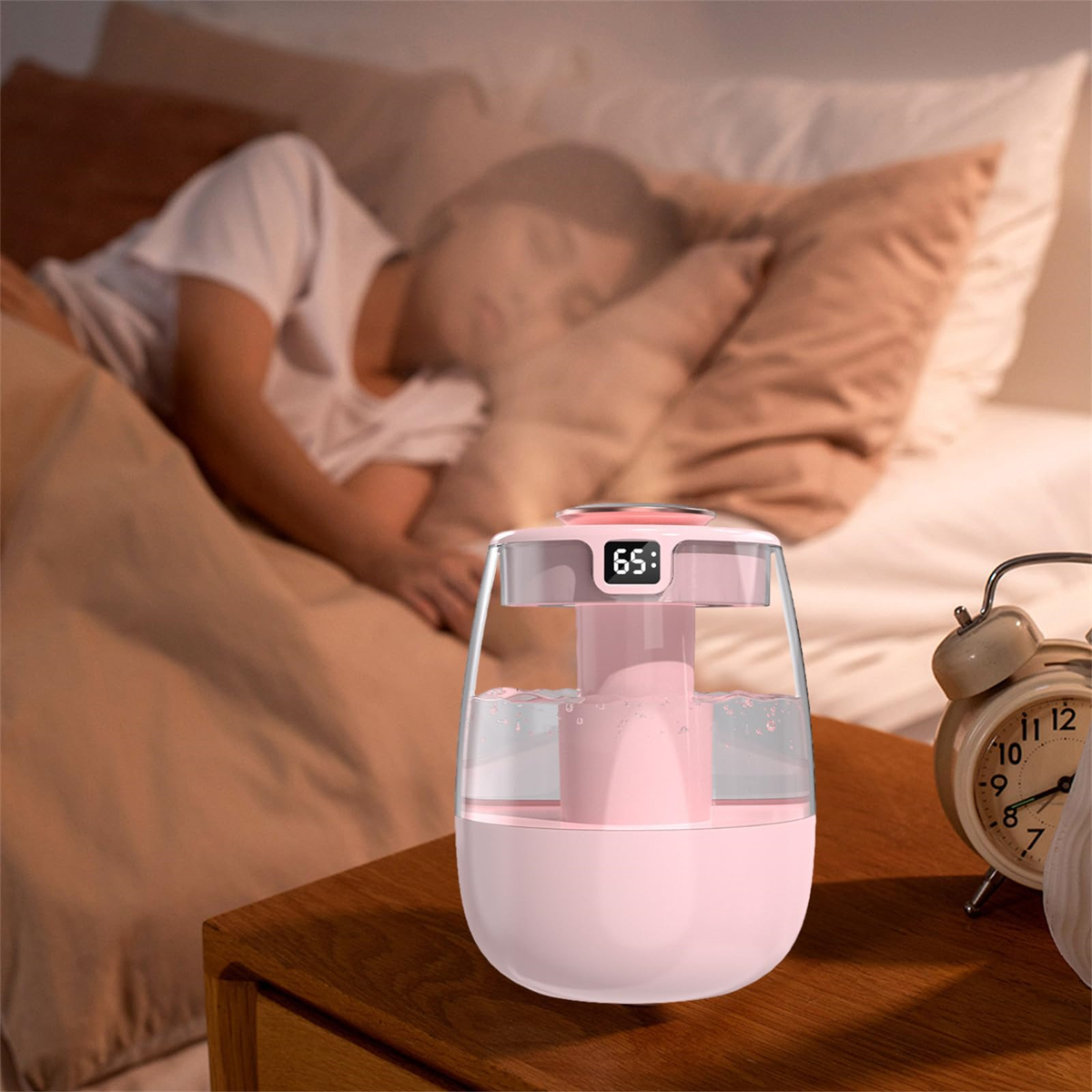 Ein rosa Luftbefeuchter auf einem Holztisch, im Hintergrund eine schlafende Person und ein Wecker.