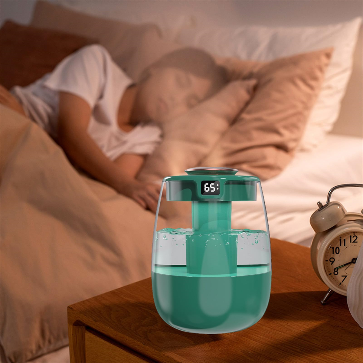 Ein Luftbefeuchter auf einem Nachttisch neben einem Bett, im Hintergrund schläft eine Person.