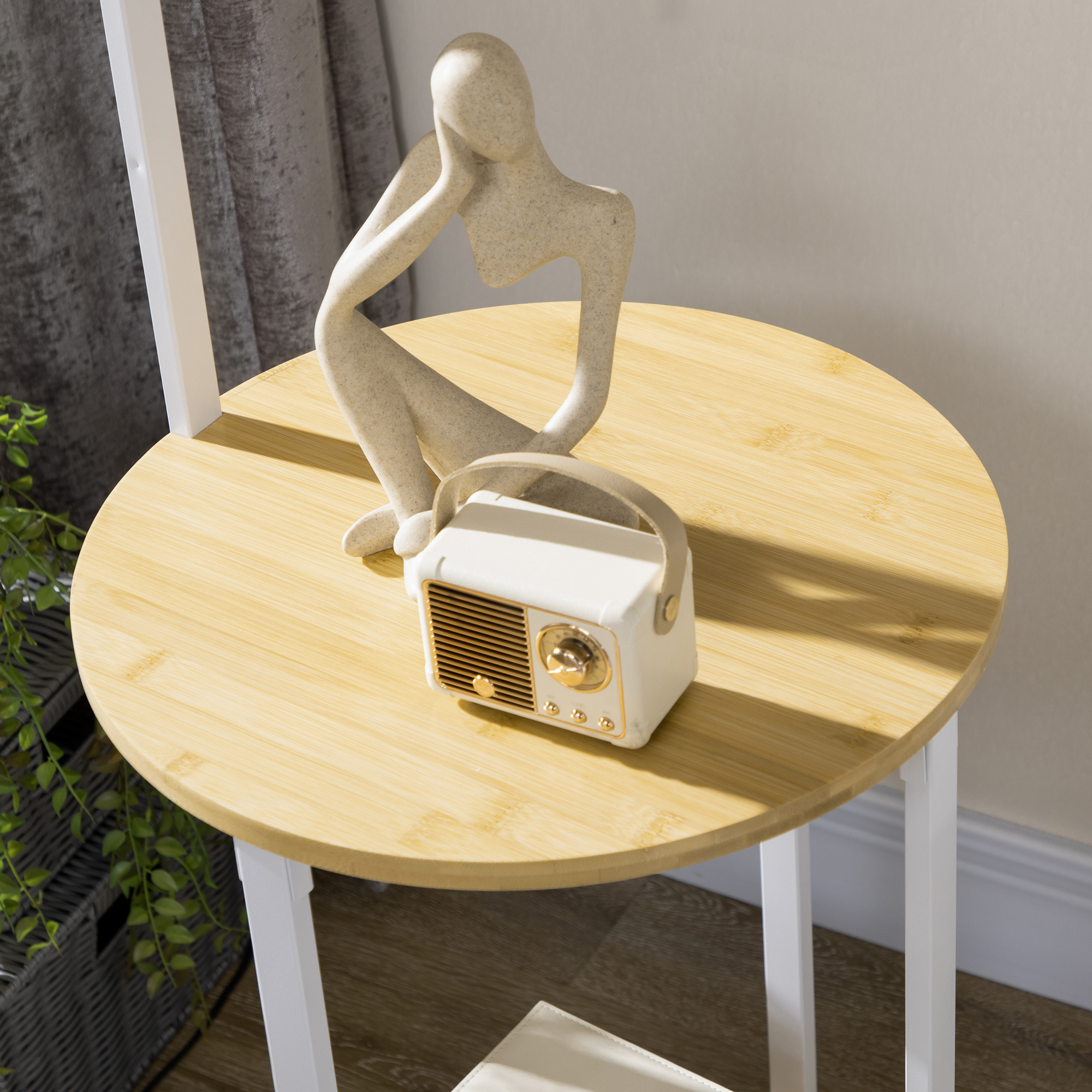 Mesa auxiliar redonda de madera con una estatua y una radio retro blanca encima.