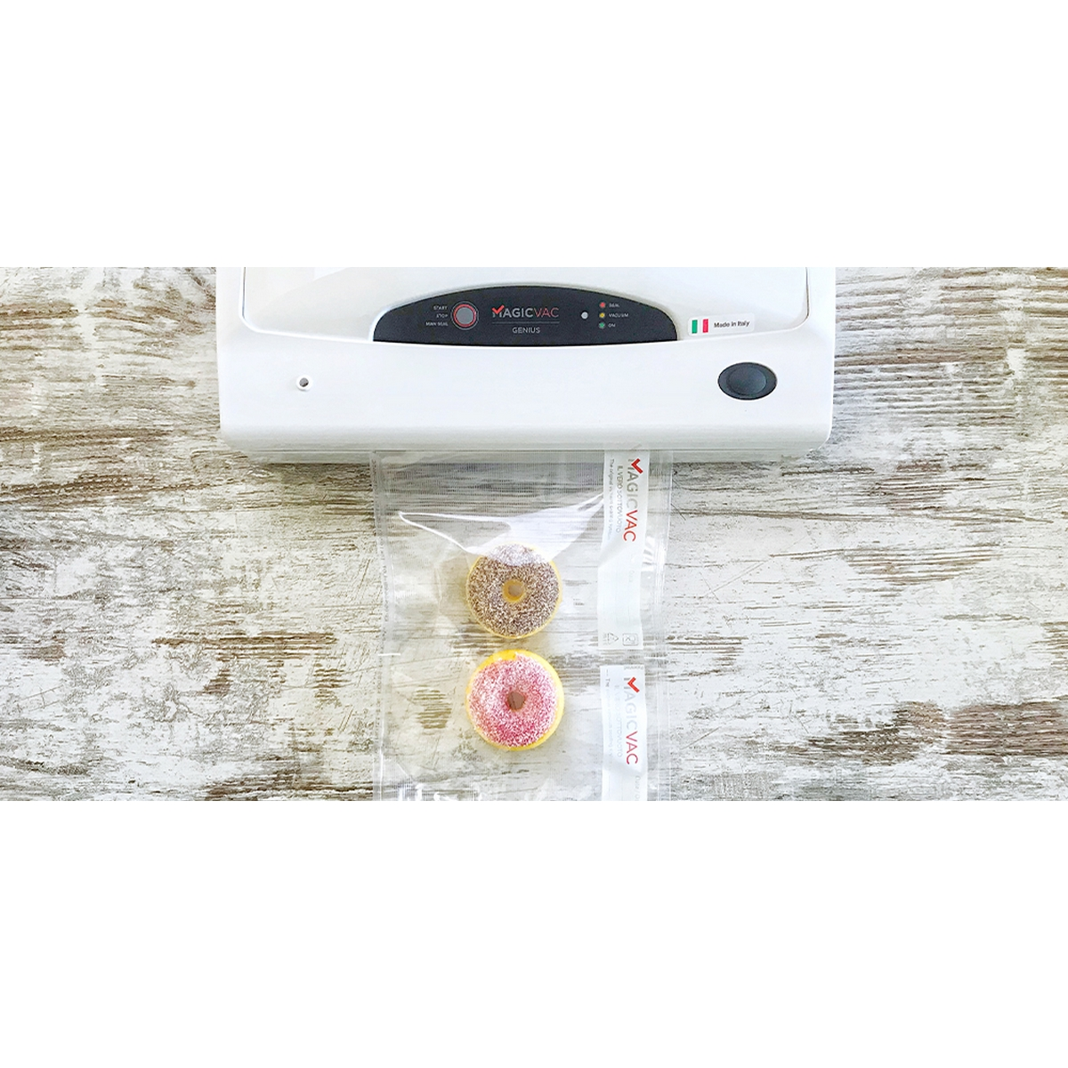 Biała zgrzewarka próżniowa z dwoma pączkami w worku próżniowym na drewnianym stole.